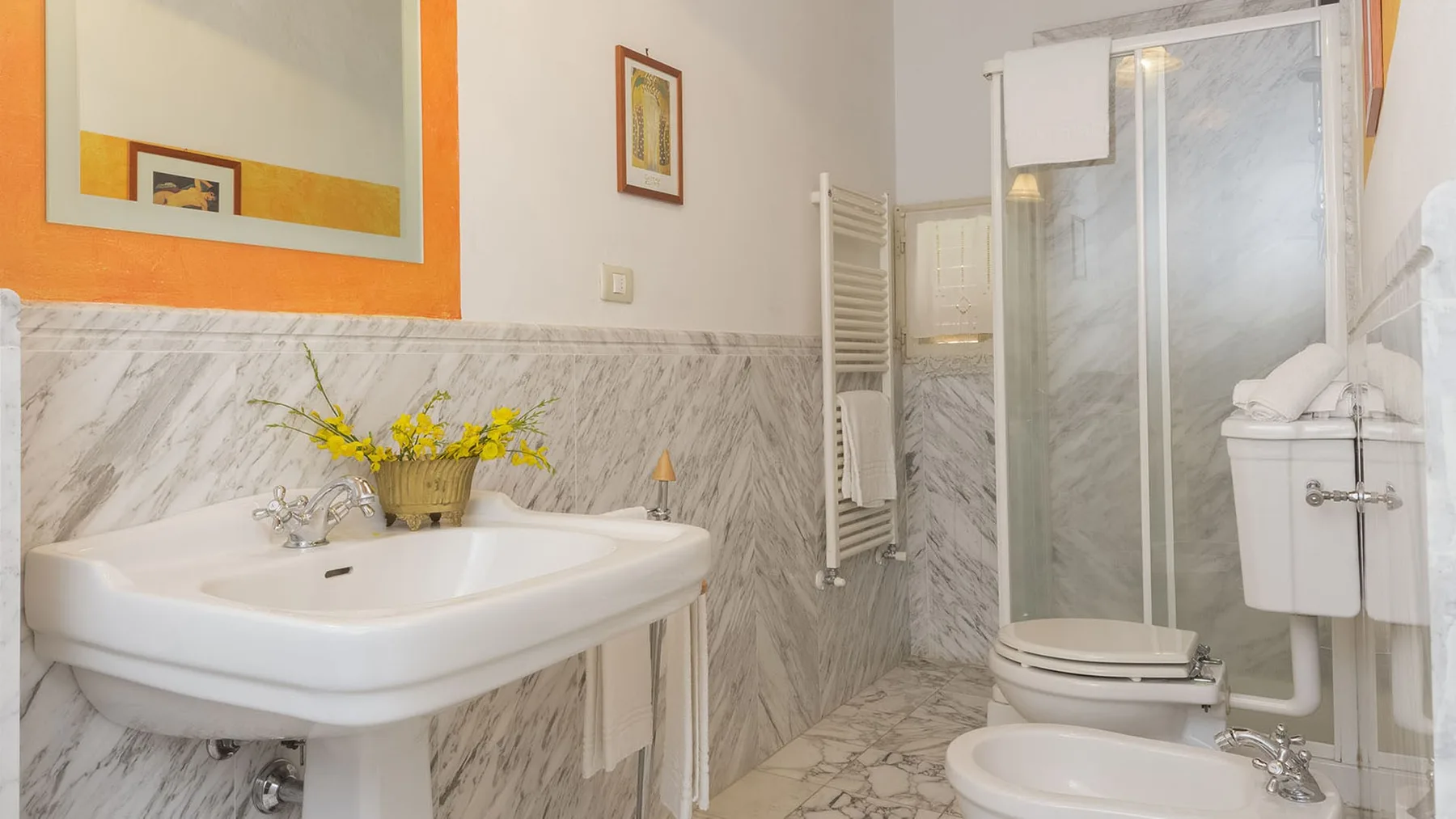 Un baño con lavabo, inodoro y ducha con mampara de vidrio.