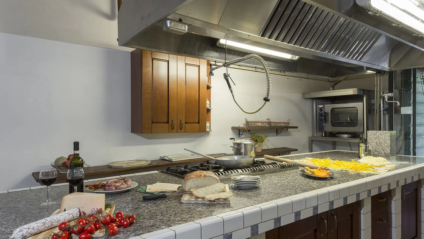 Una cocina comercial con una encimera larga, equipo de cocina y ventilación superior.