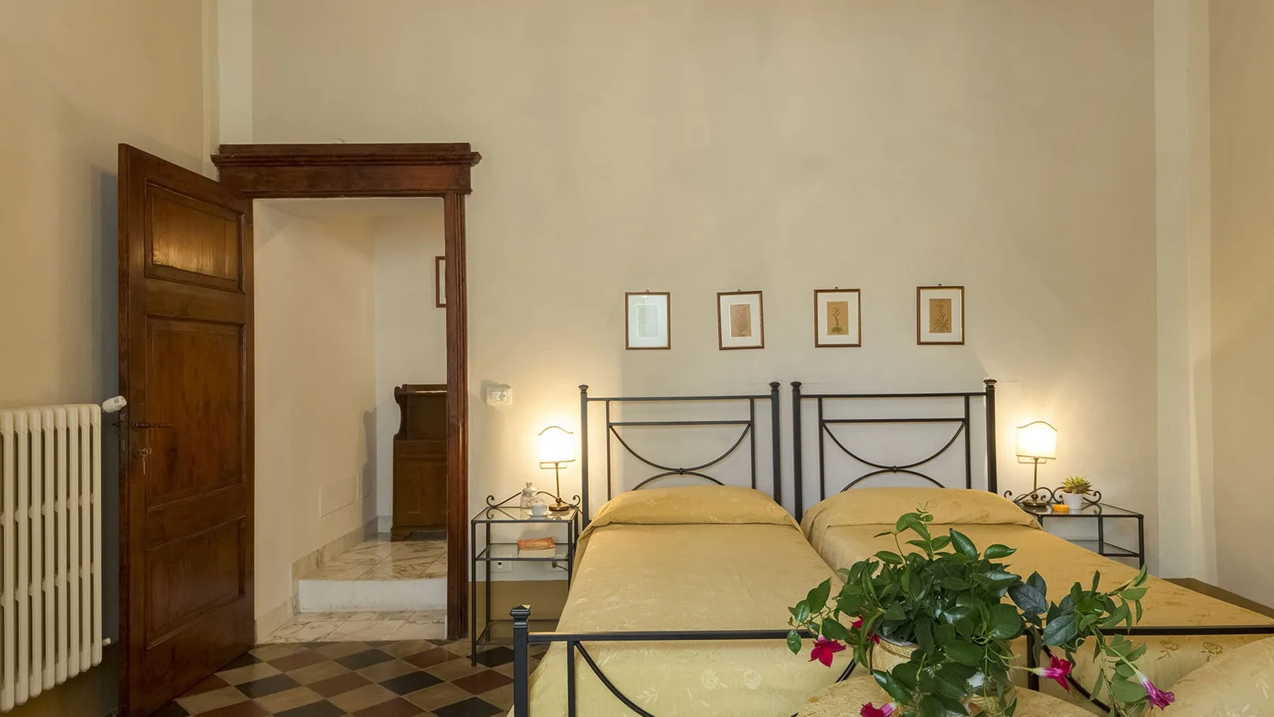 Un dormitorio con dos camas, mesitas de noche y una planta en maceta.