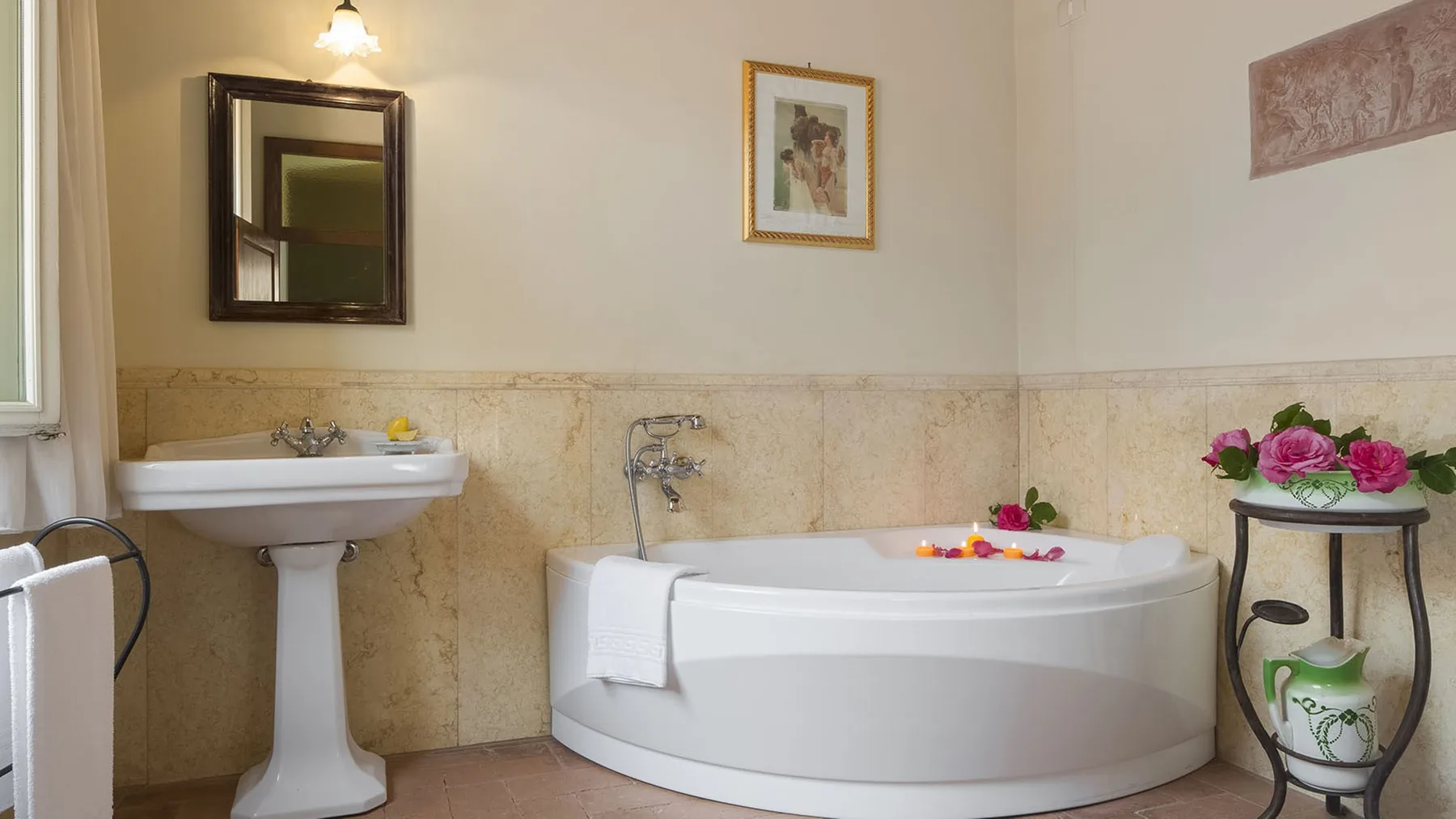 Un baño con bañera, lavabo con pedestal y flores.