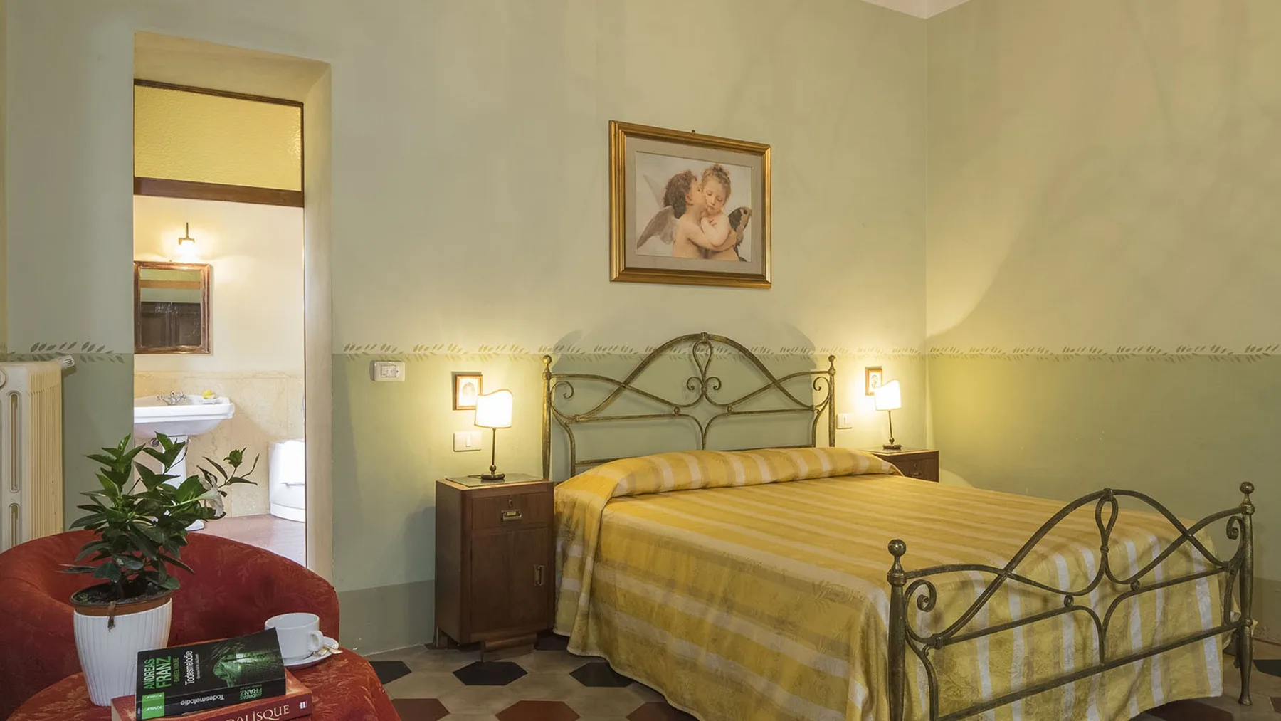 Un dormitorio con una cama de metal, mesitas de noche y una puerta al baño.