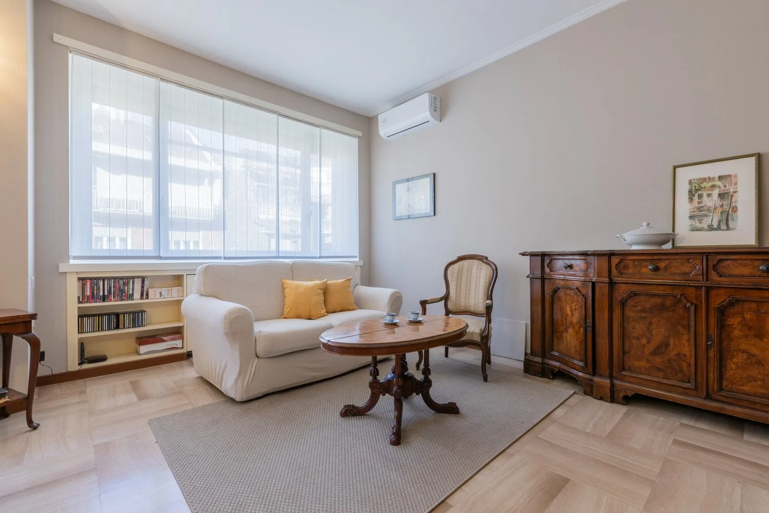 A bright living room with a loveseat, a coffee table, and a wooden cabinet.
