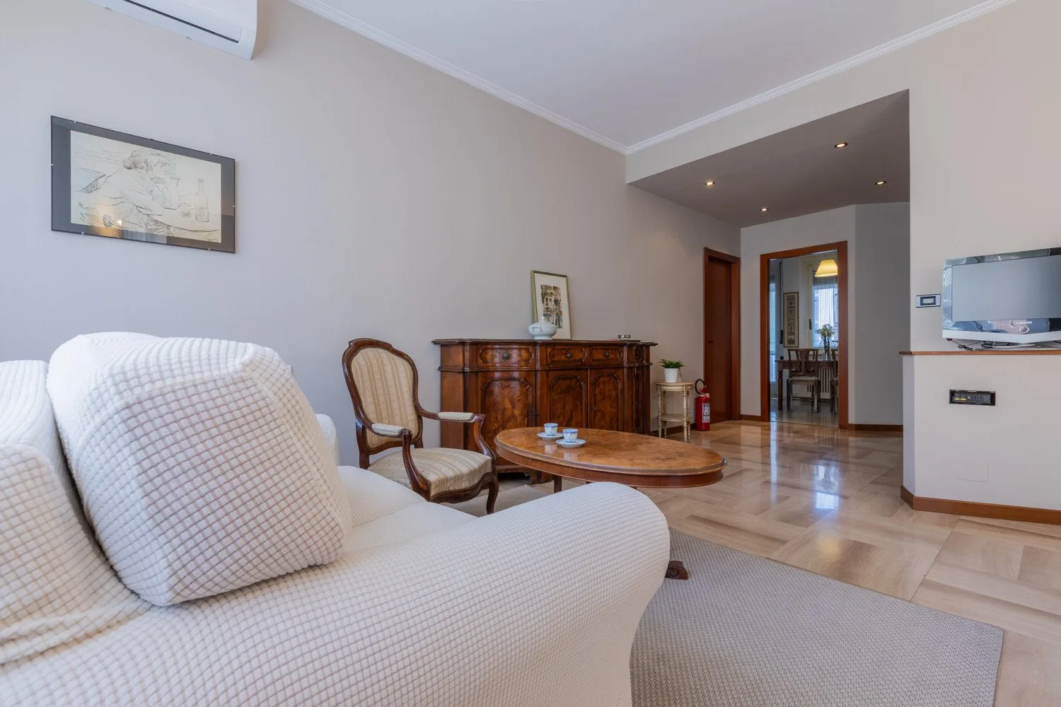 A bright living room with seating, a wooden coffee table, and a cabinet.