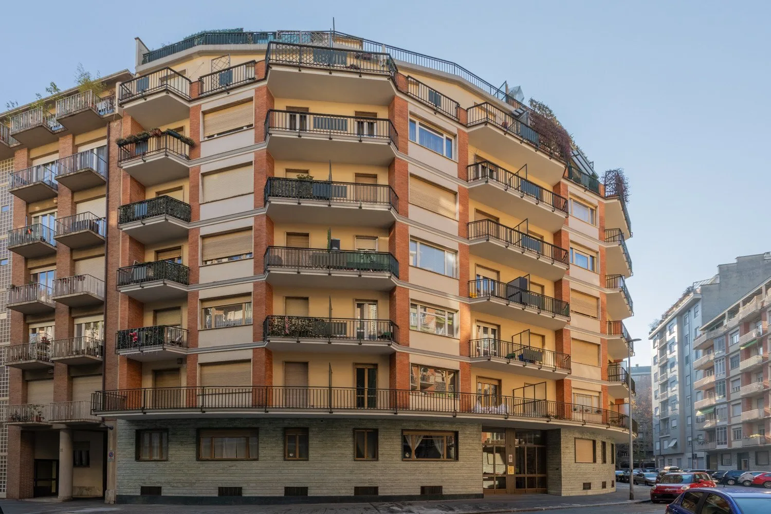 A multi-story apartment building with balconies stands along an urban street.