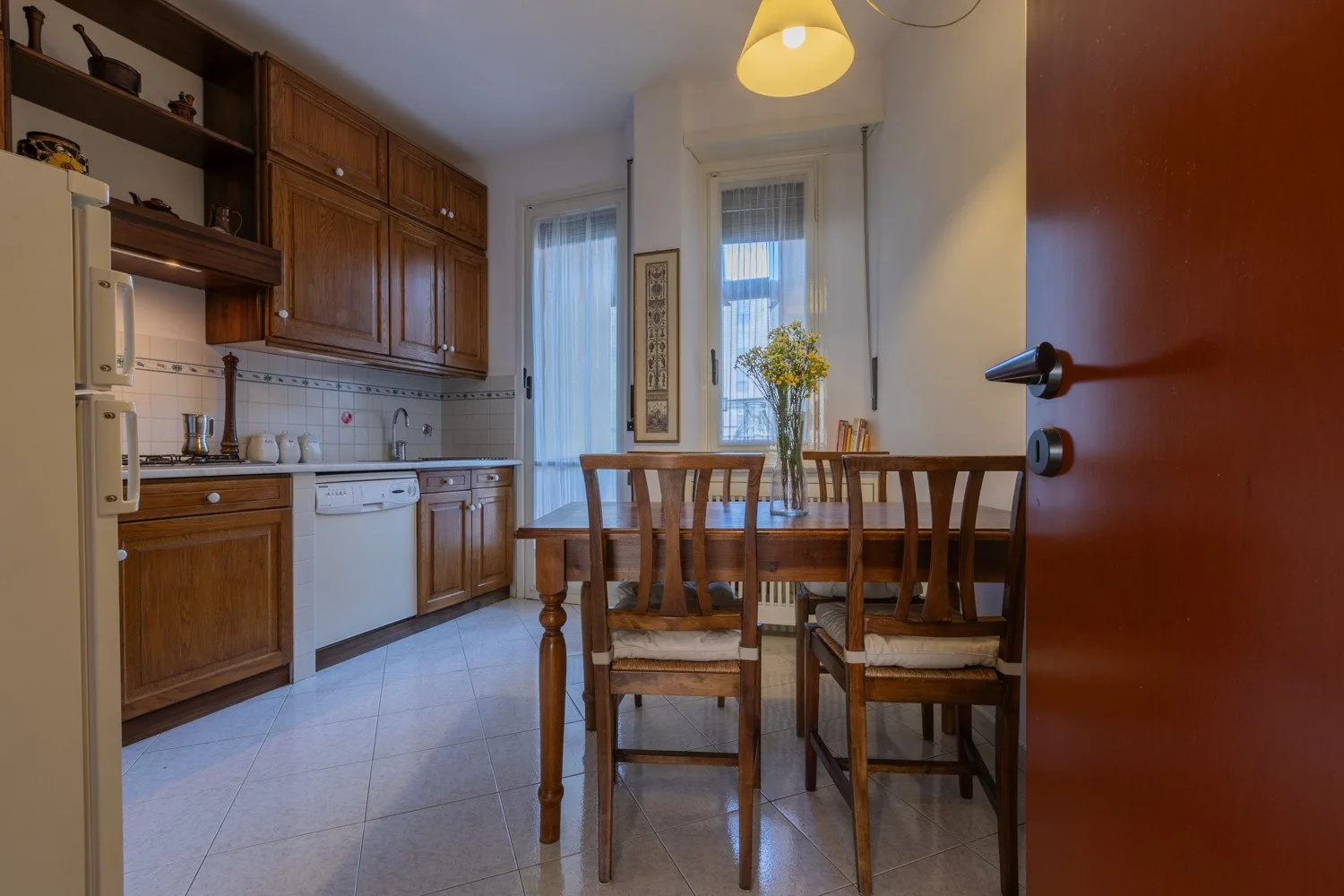 A kitchen dining area with wooden cabinetry and a table beside the windows.
