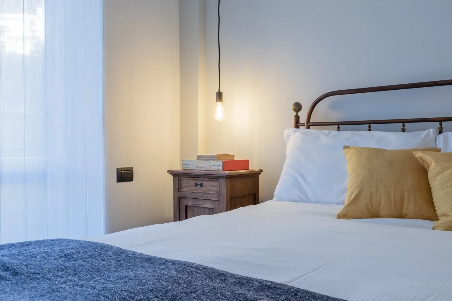 A bedroom with a neatly made bed and a small bedside table.
