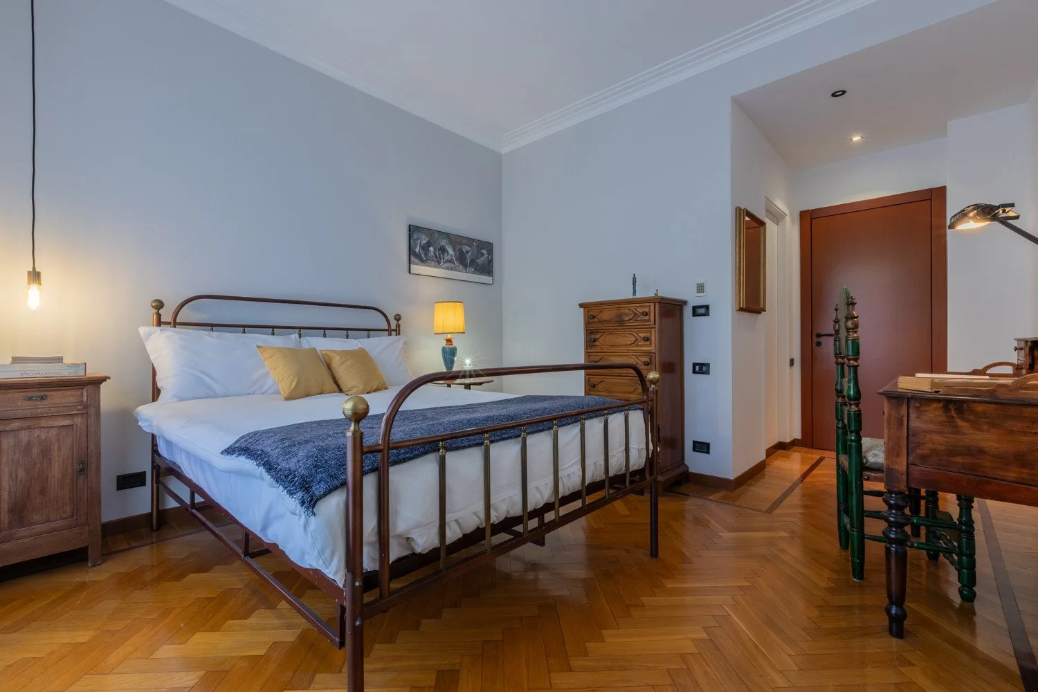 A bedroom with a metal-framed bed and wooden furniture.