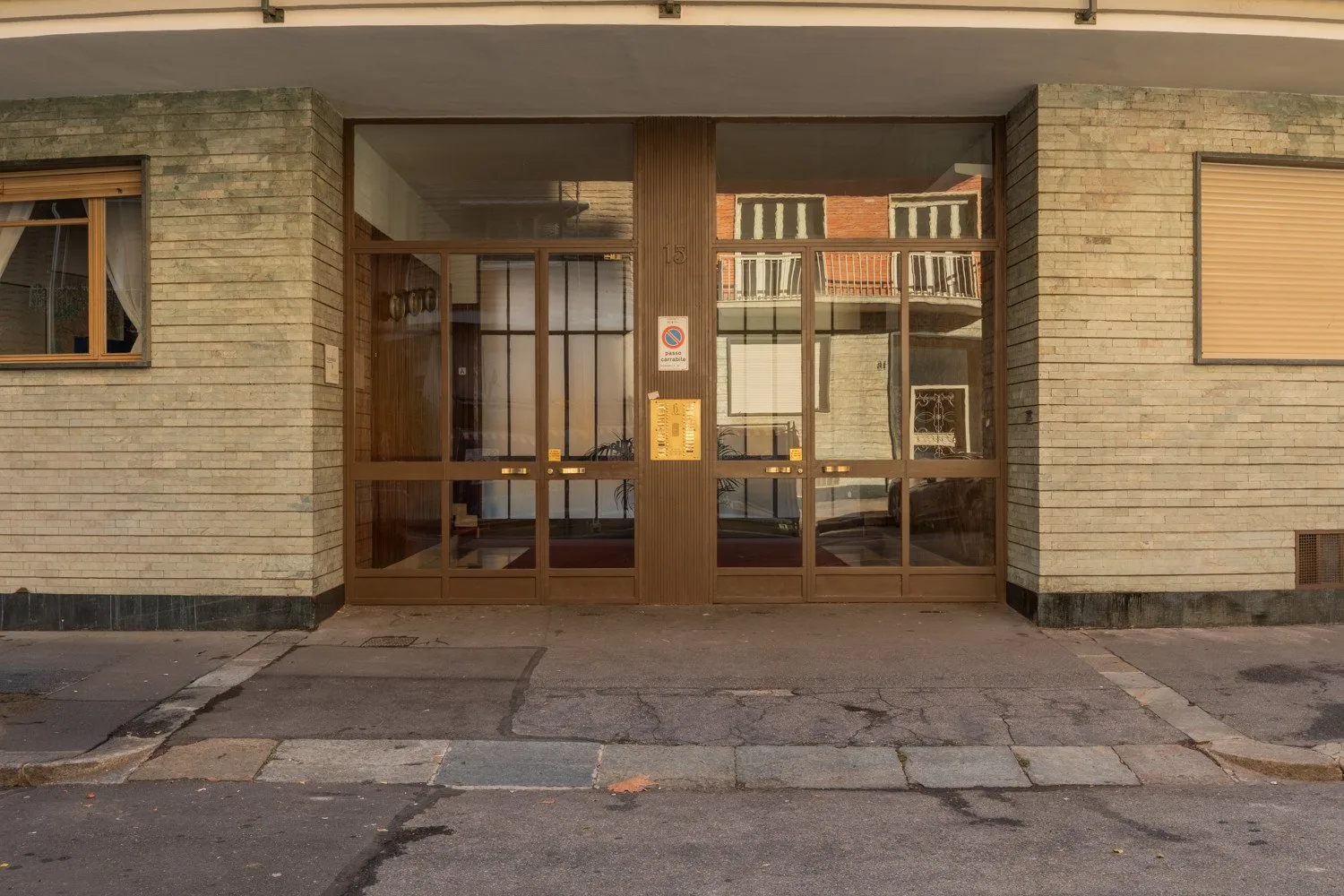 A building entrance with glass doors set into a stone facade.