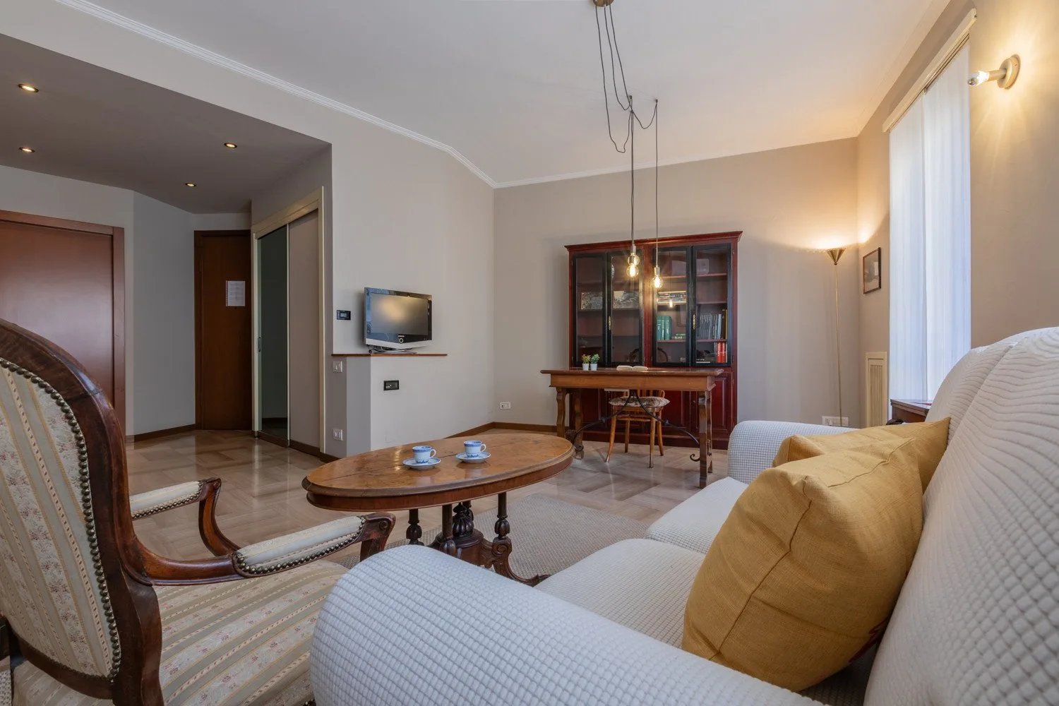 A living room with upholstered seating, a coffee table, and a wooden display cabinet.