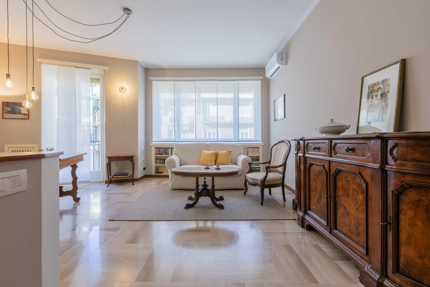 A bright living room with seating arranged around a small table beneath a large window.