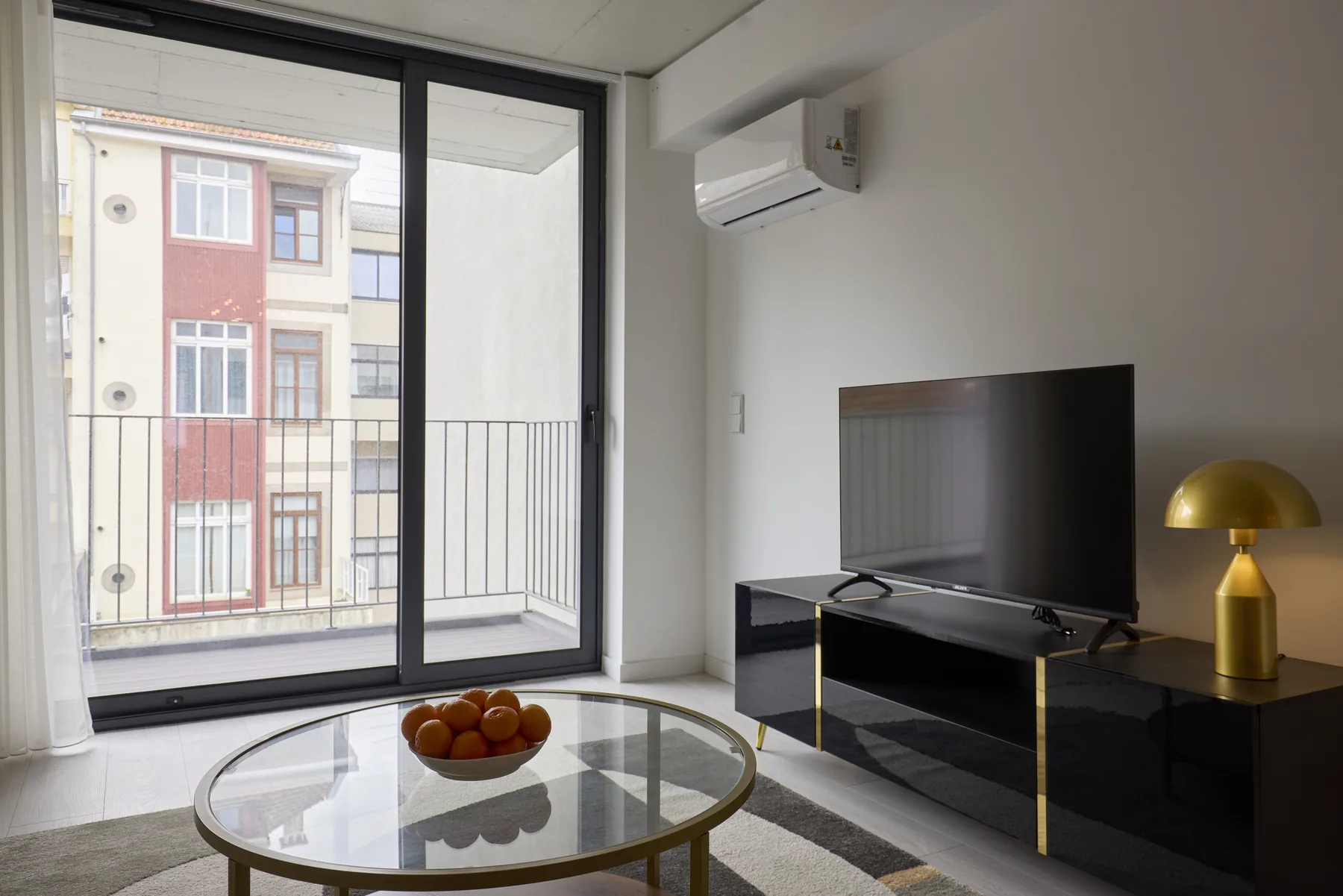 A living room with a television, coffee table, and glass doors opening to a balcony.