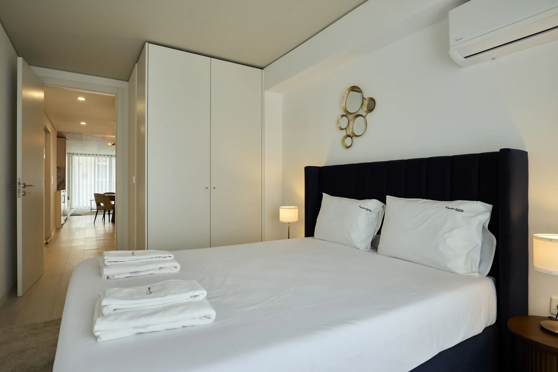 A bedroom with a neatly made bed and folded towels.