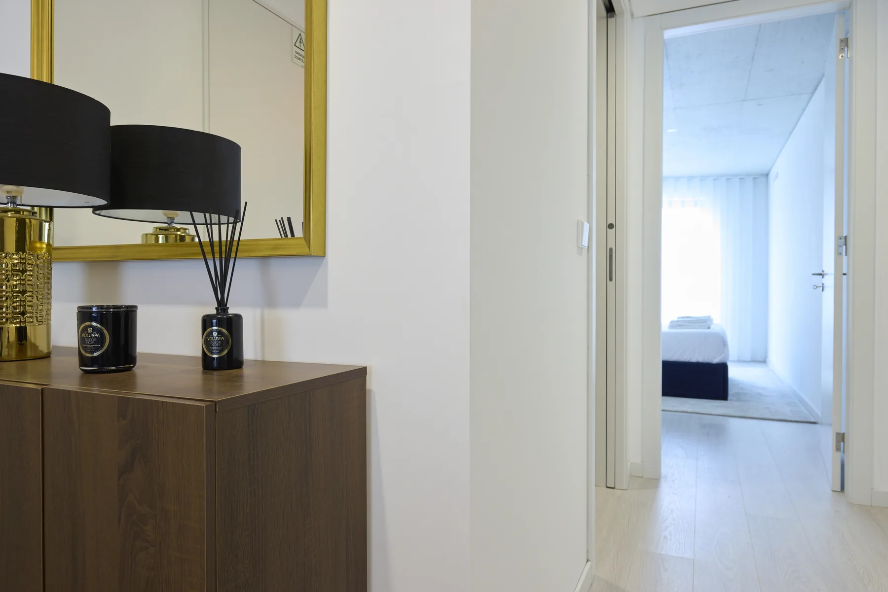 A hallway with a wooden console table and an open doorway to a bright room.