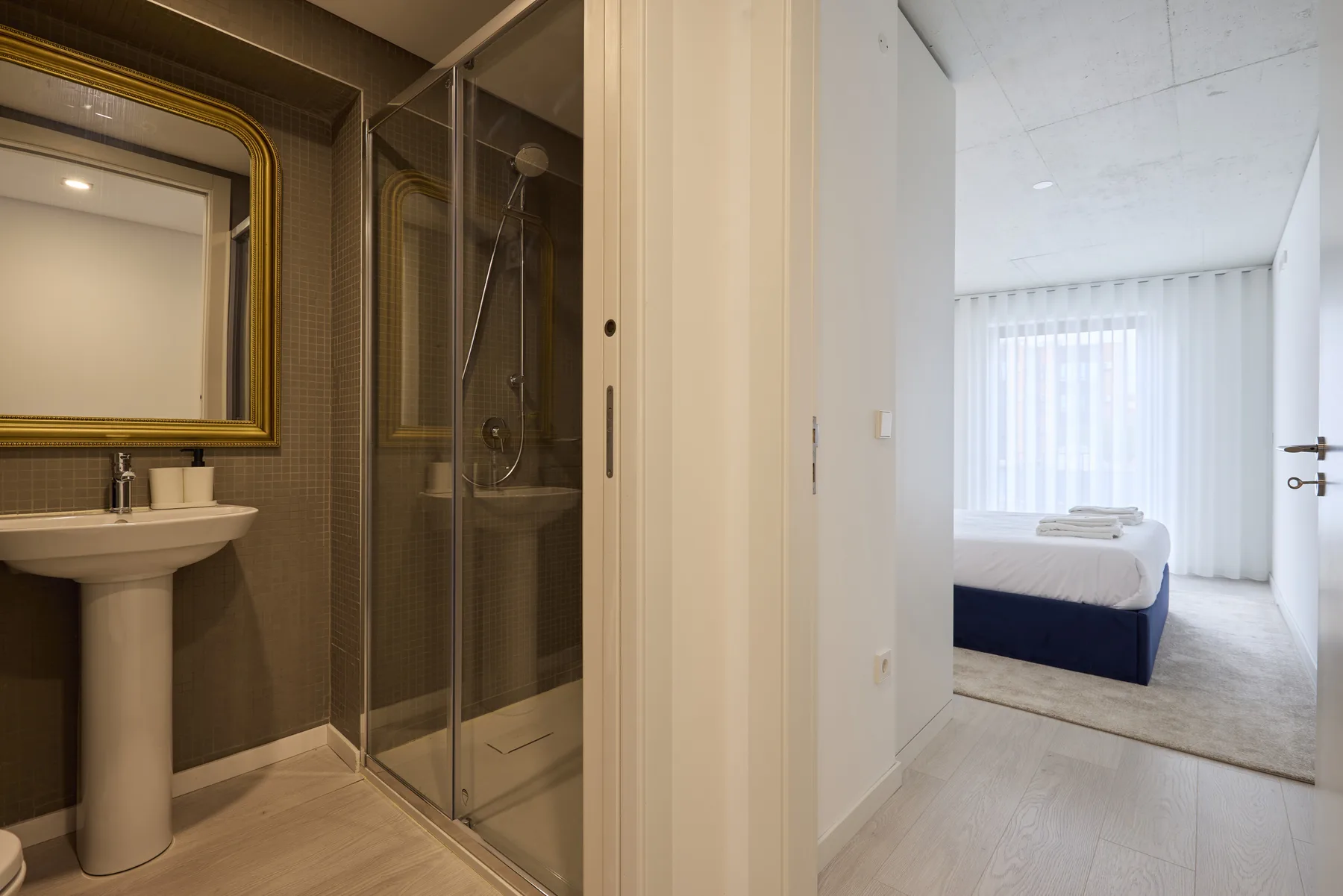 A bedroom with a neatly made bed beside an adjoining bathroom.