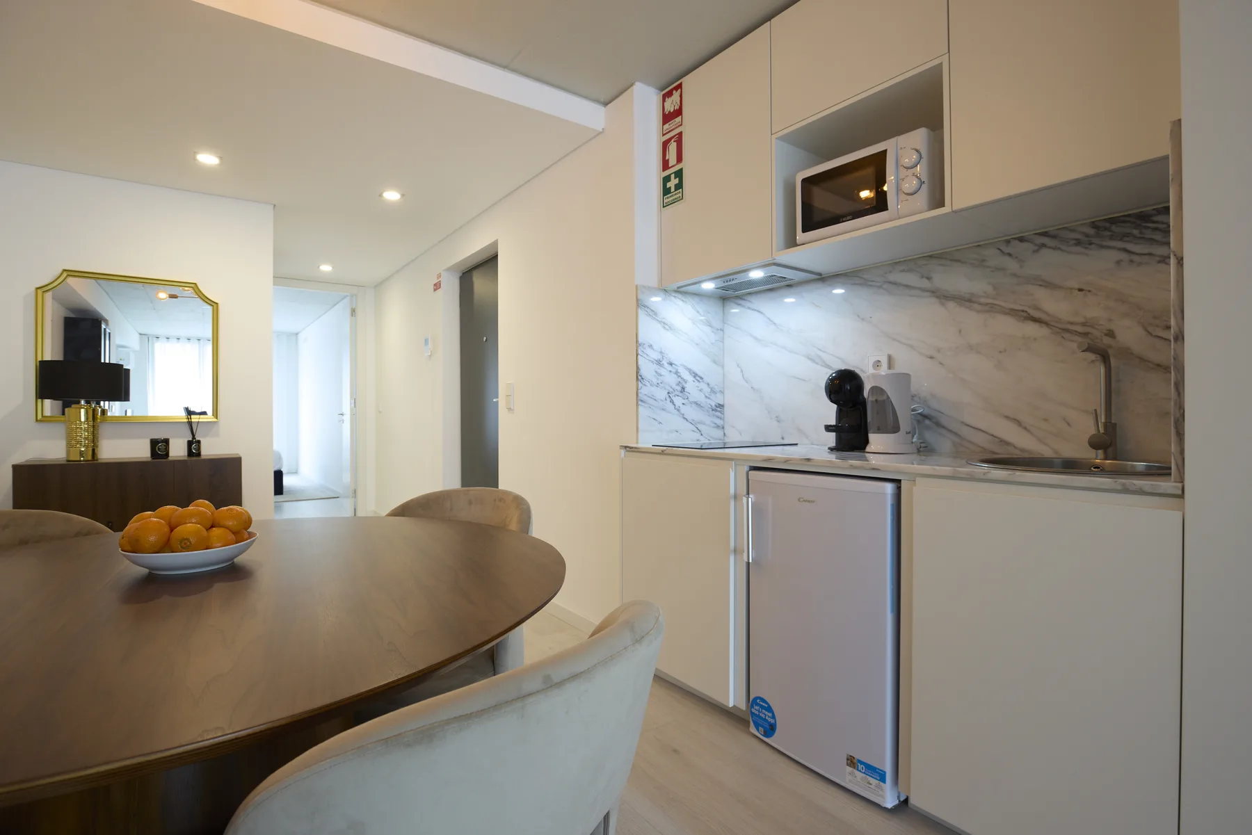 A compact kitchen with a dining table and a marble-patterned backsplash.