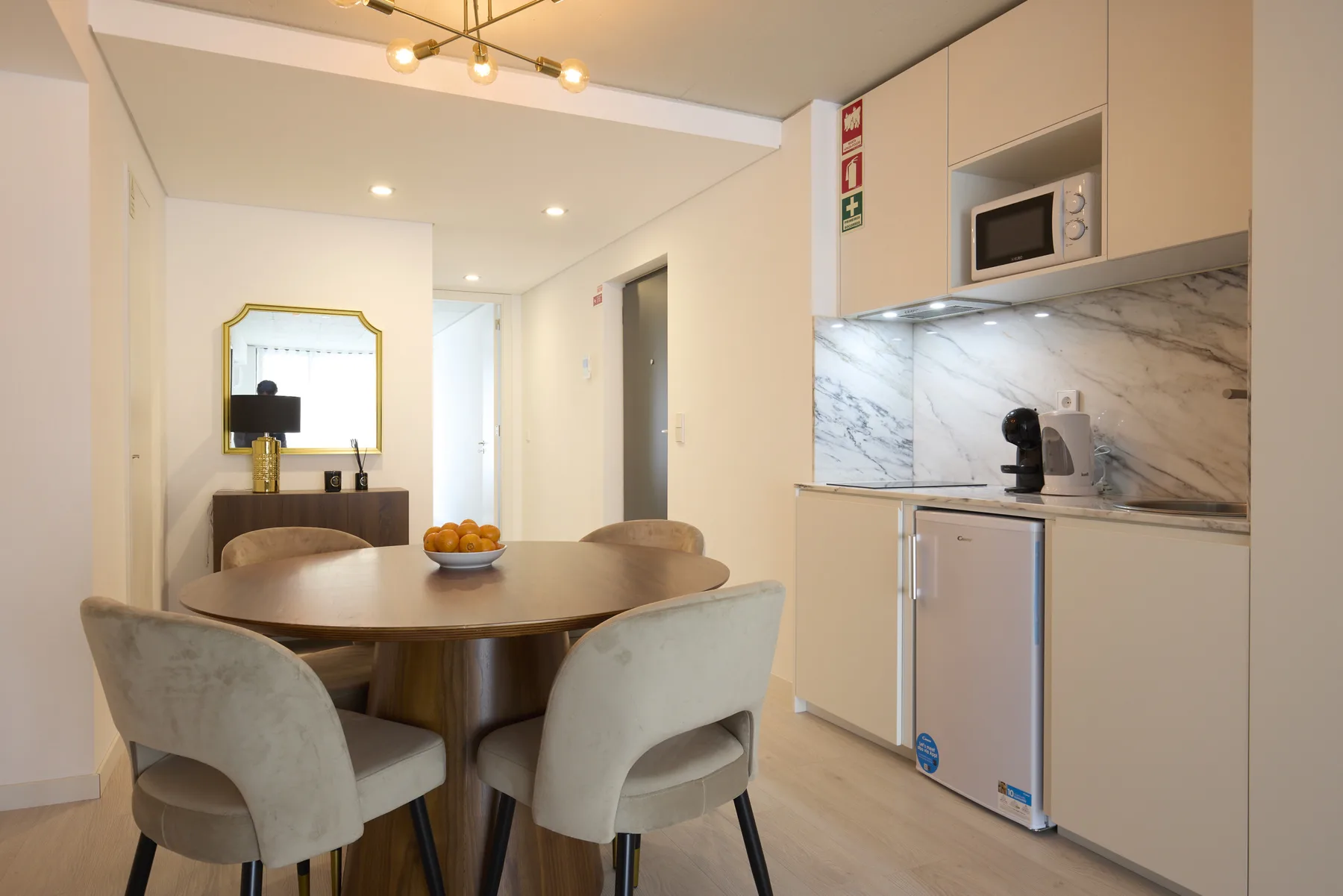 A dining area with a round table and an adjoining compact kitchen.