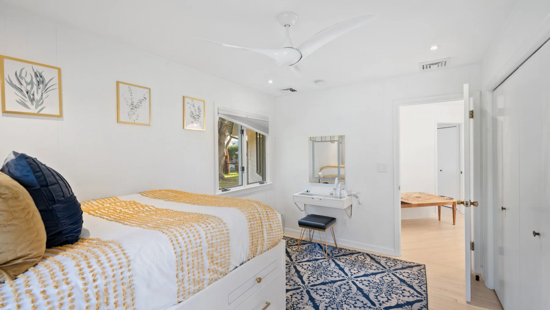 Un dormitorio luminoso con una cama, cuadros y una puerta abierta.
