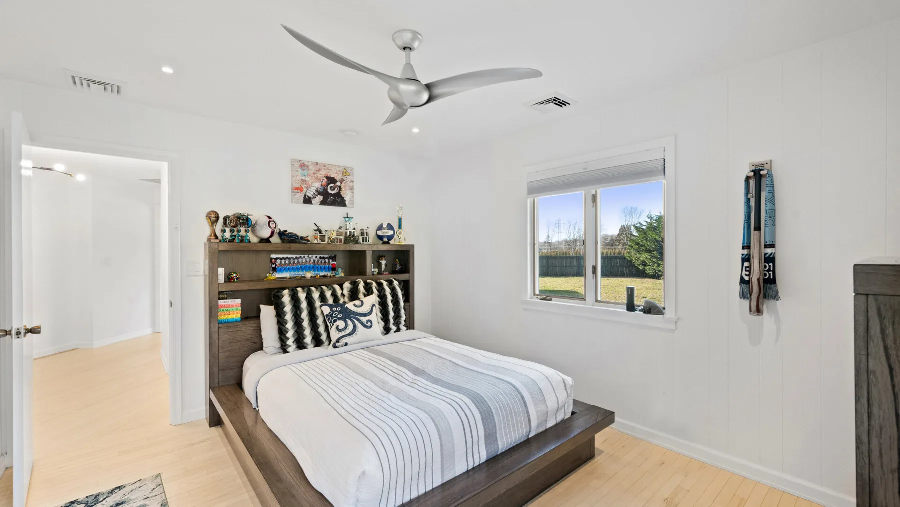 Un dormitorio luminoso con una cama bien hecha y una ventana con vistas a zonas verdes.
