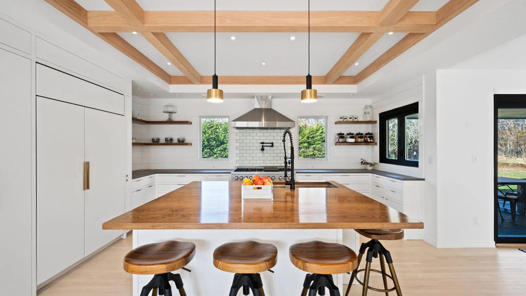 Una cocina luminosa con una gran isla de madera y lámparas colgantes.
