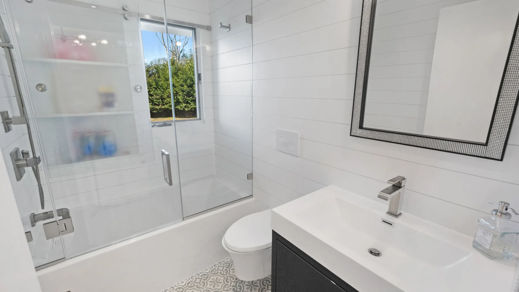 Un baño luminoso con ducha, inodoro y lavabo.