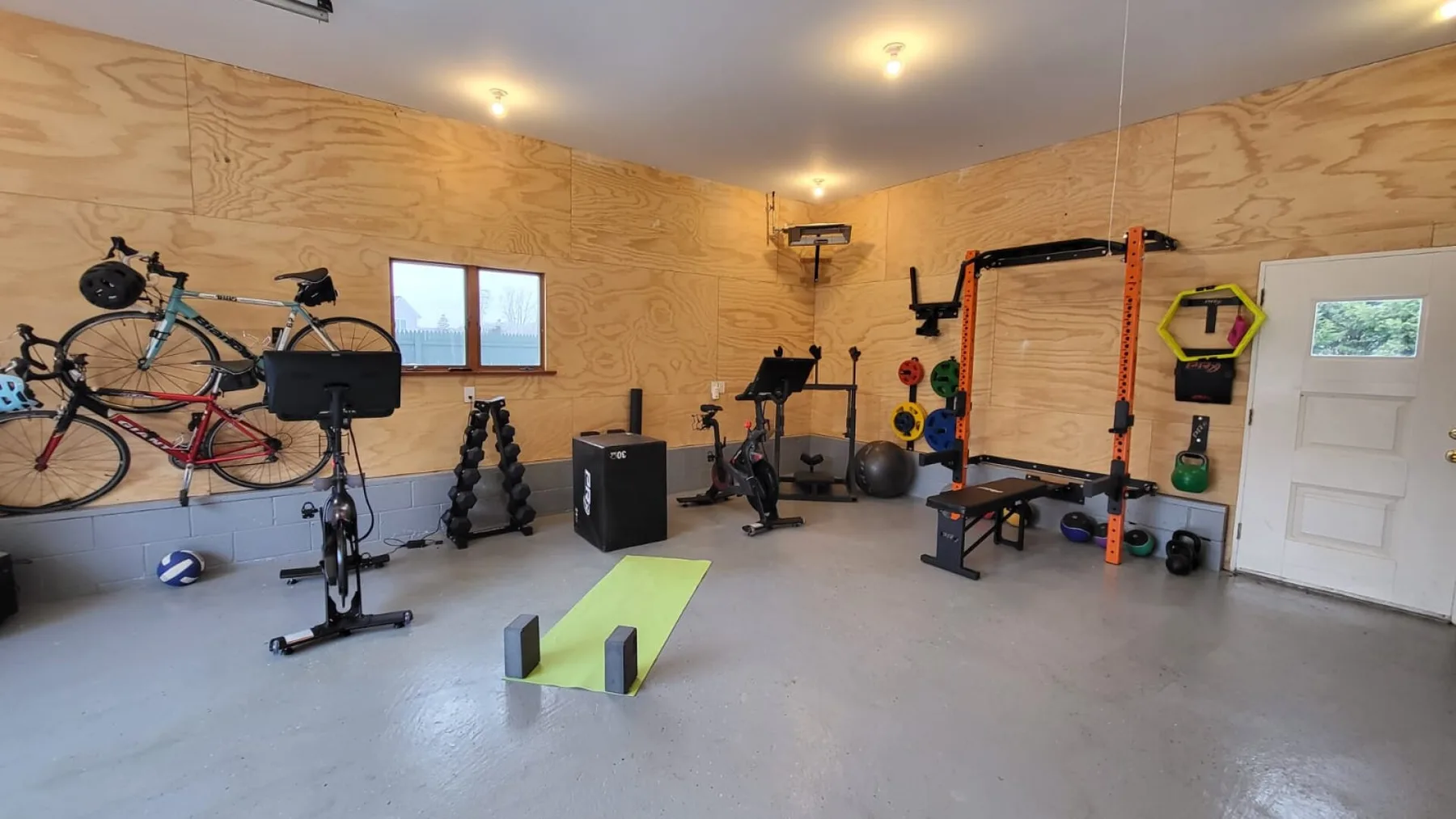 Un gimnasio en casa con equipo de ejercicio, bicicletas y una estructura de pesas.