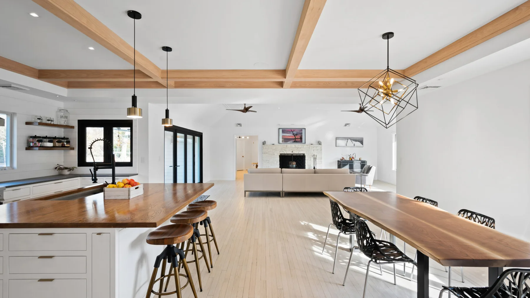 Una cocina abierta con comedor, mesas largas de madera y una zona de estar central.