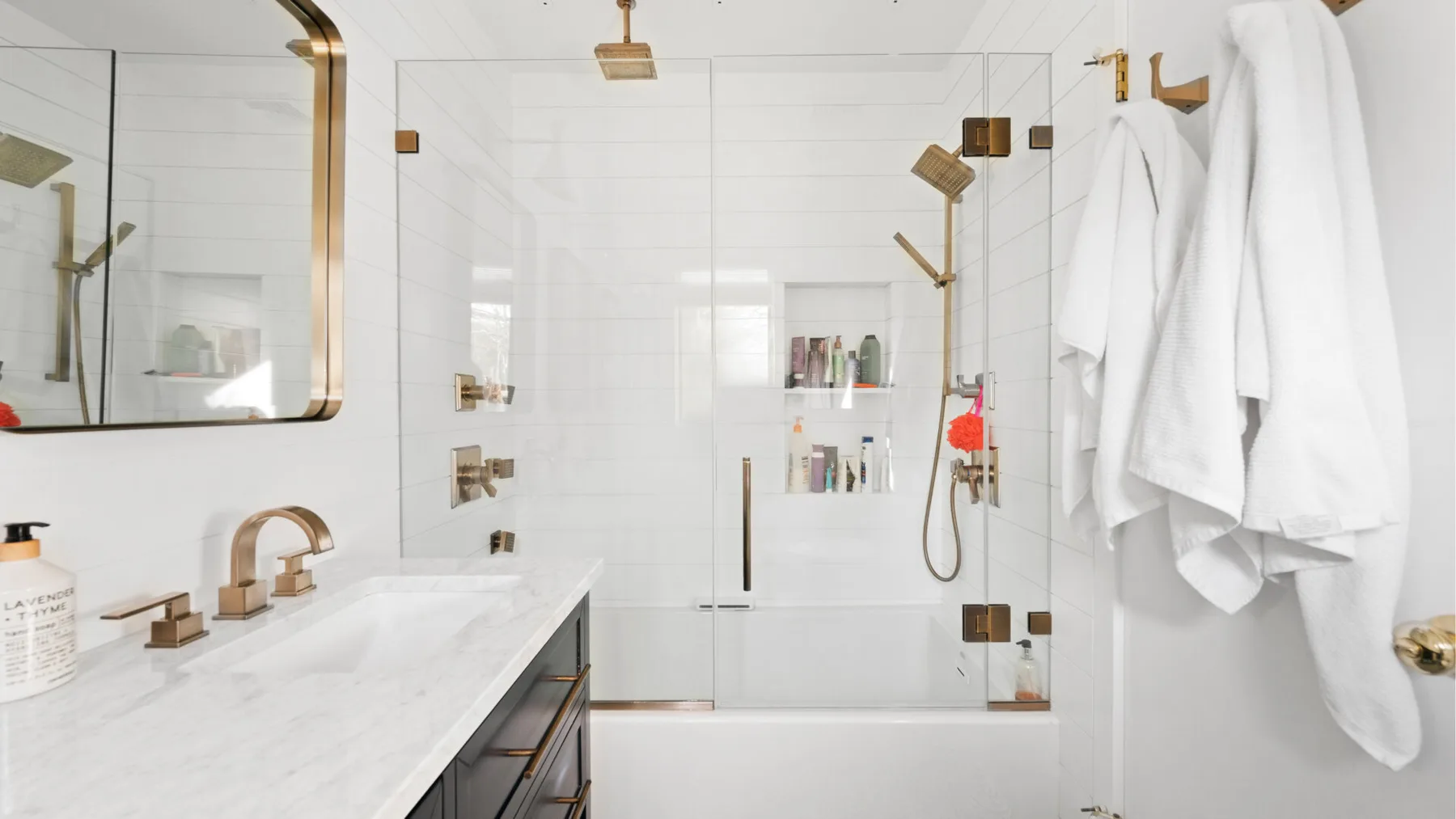 Un baño luminoso con una ducha de vidrio y toallas blancas.