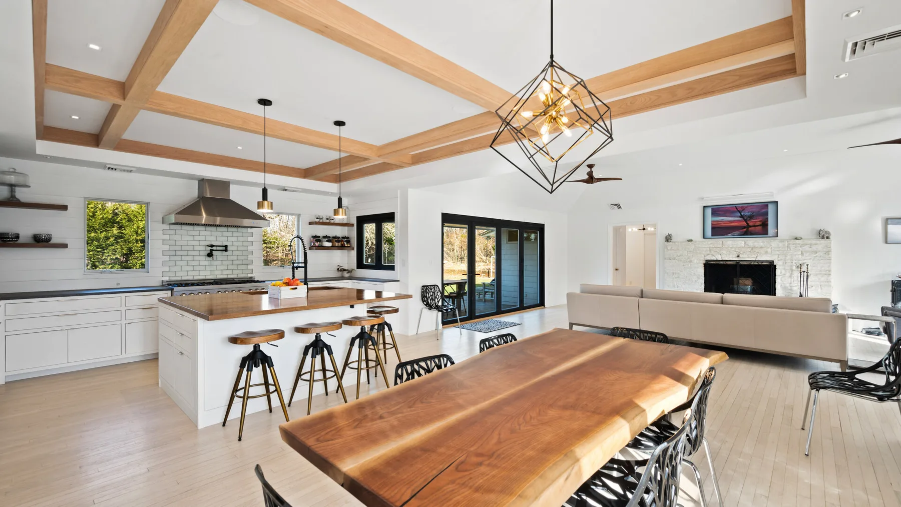 Una cocina y sala de estar diáfanas y luminosas con una larga mesa de madera.