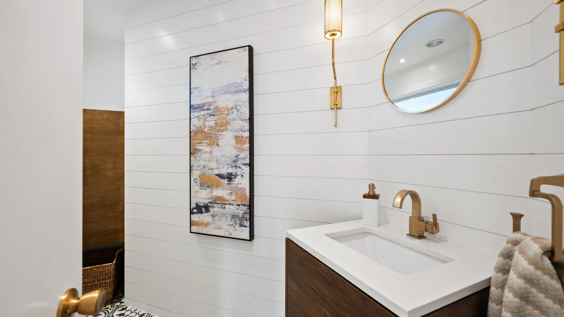 Un tocador de baño con lavabo rectangular, espejo de pared y cuadro enmarcado.
