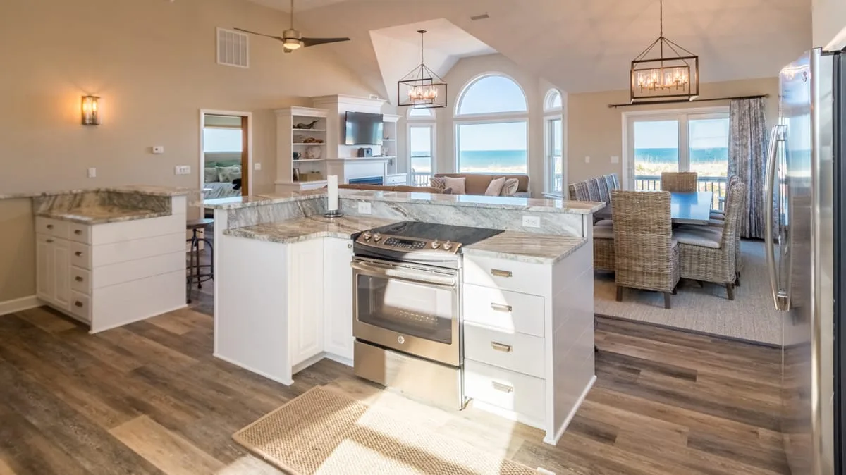 Una cocina abierta y comedor con una isla central y ventanas grandes.