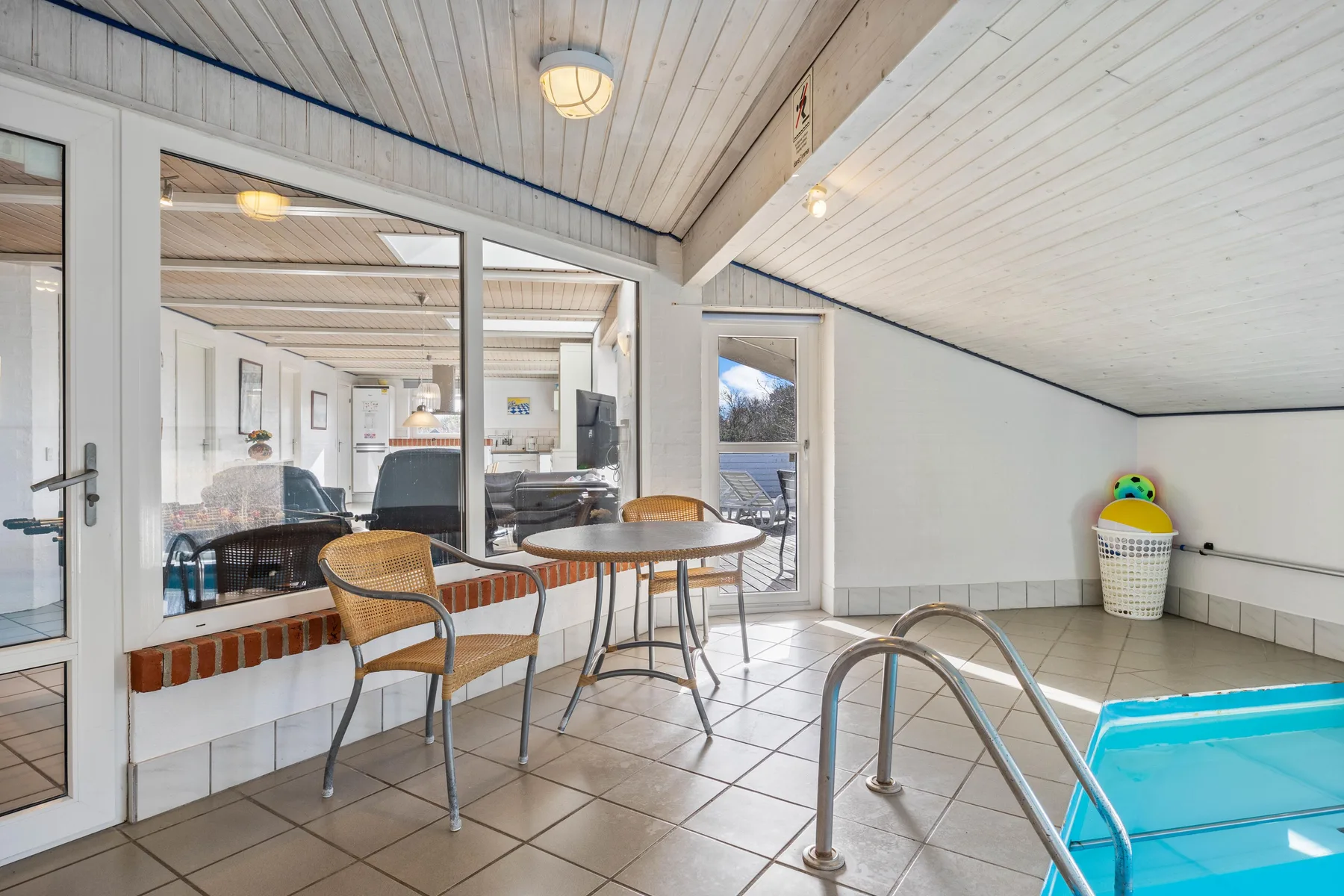 Una zona de piscina cubierta con una mesa pequeña y asientos junto al agua.