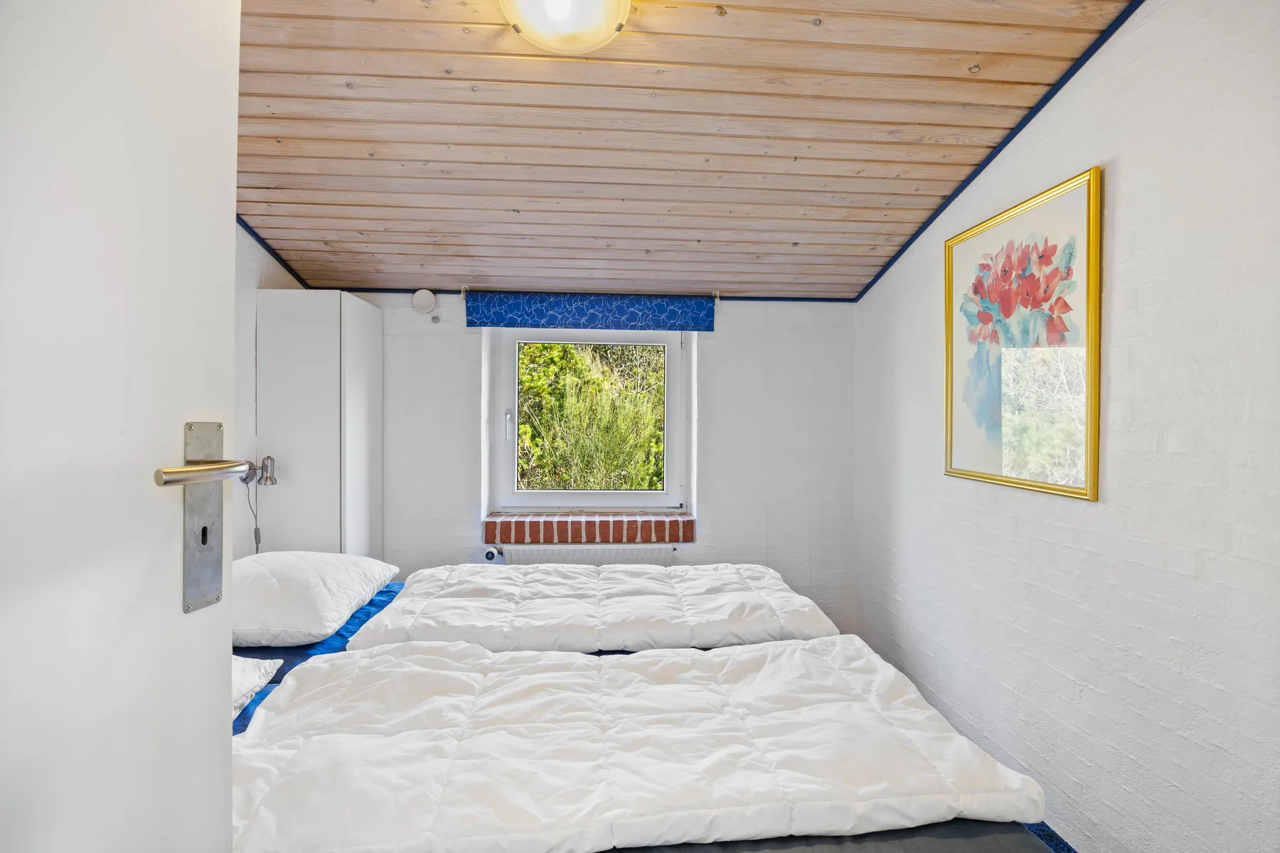 Un dormitorio con dos camas bajo un techo inclinado revestido de madera.