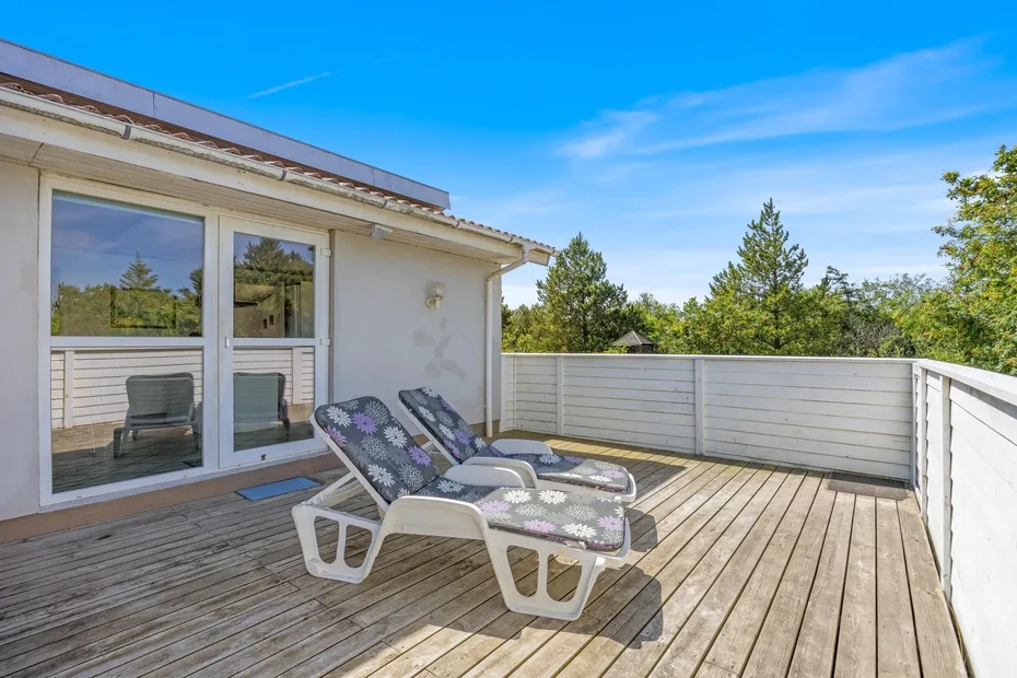 Una terraza exterior con asientos reclinables y puertas corredizas de vidrio.