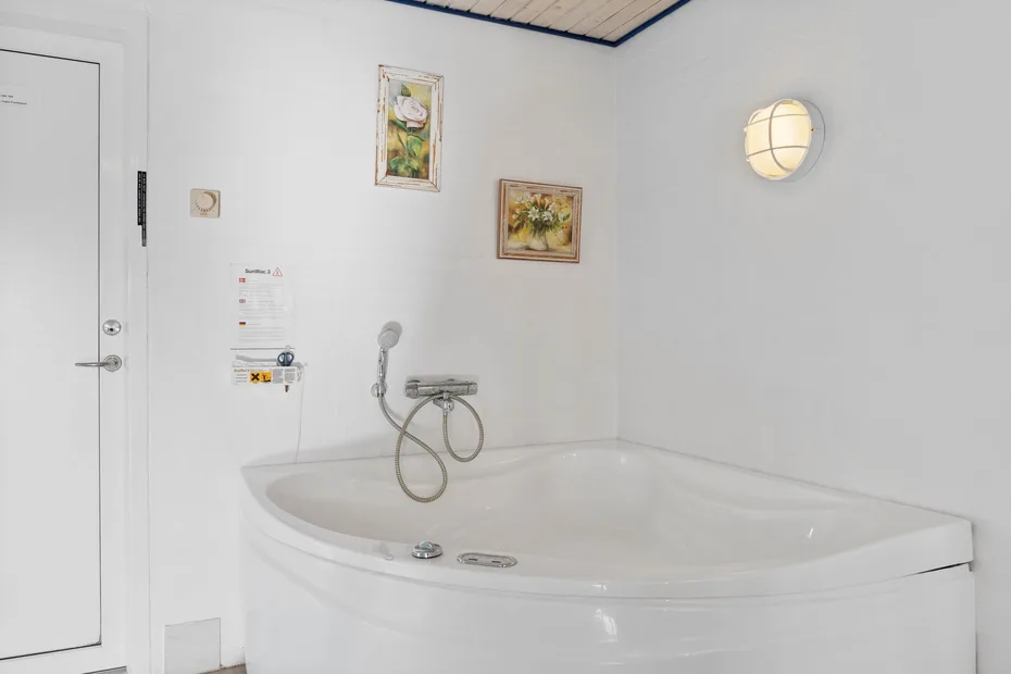 Un baño con una bañera grande, ducha de pared y cuadros enmarcados.
