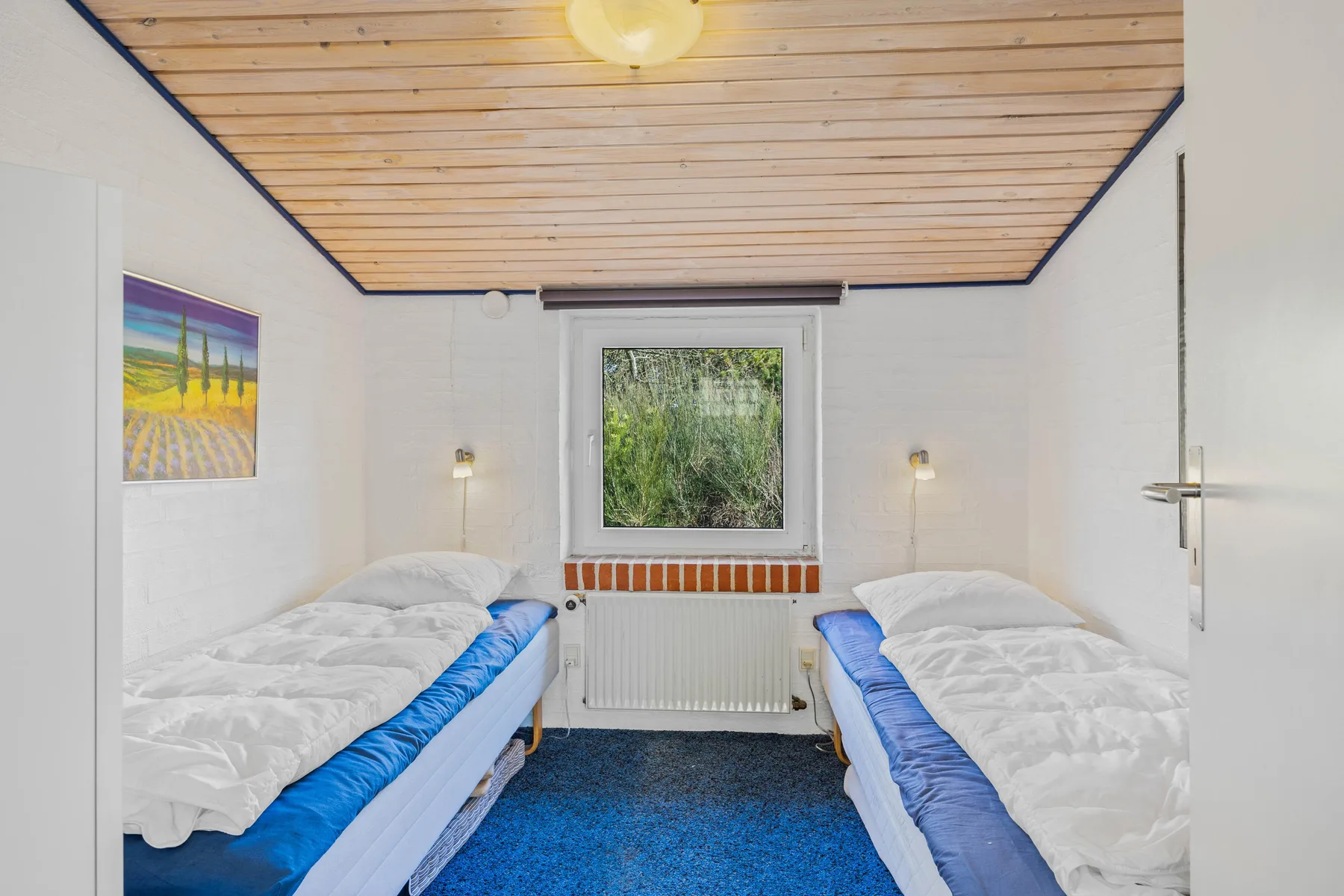 Un dormitorio con dos camas, una ventana y un techo inclinado de madera.
