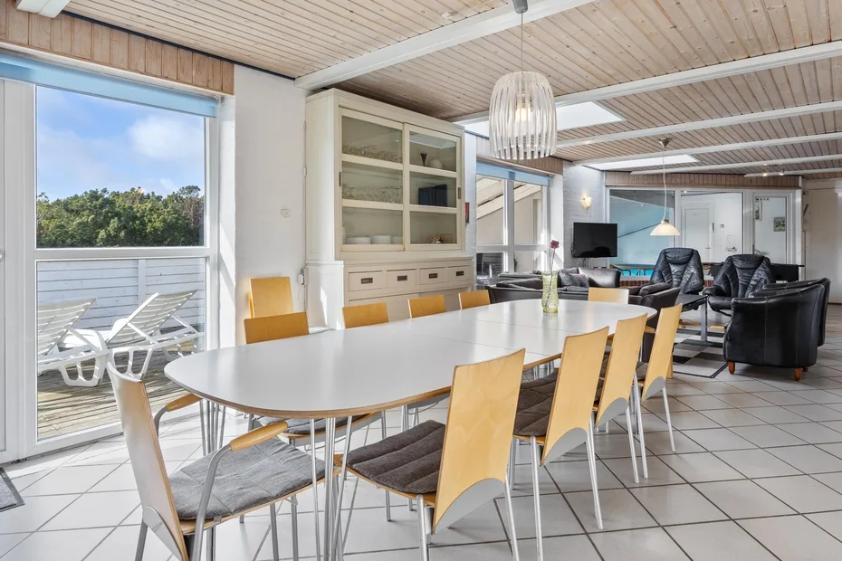 Un comedor luminoso con una mesa larga y asientos junto a grandes ventanales.