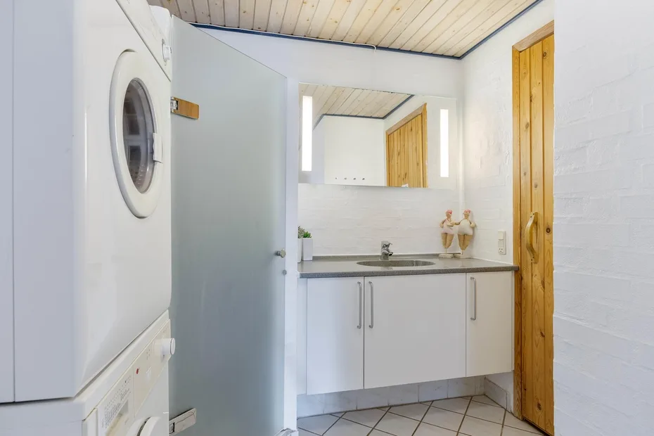 Un baño compacto con lavabo, espejo y armarios blancos.