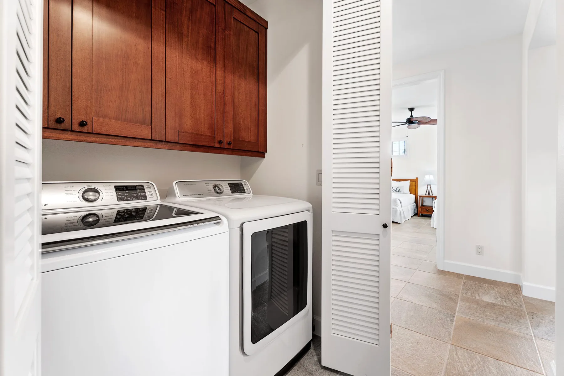 A laundry area with a washer and dryer beneath wooden cabinets.