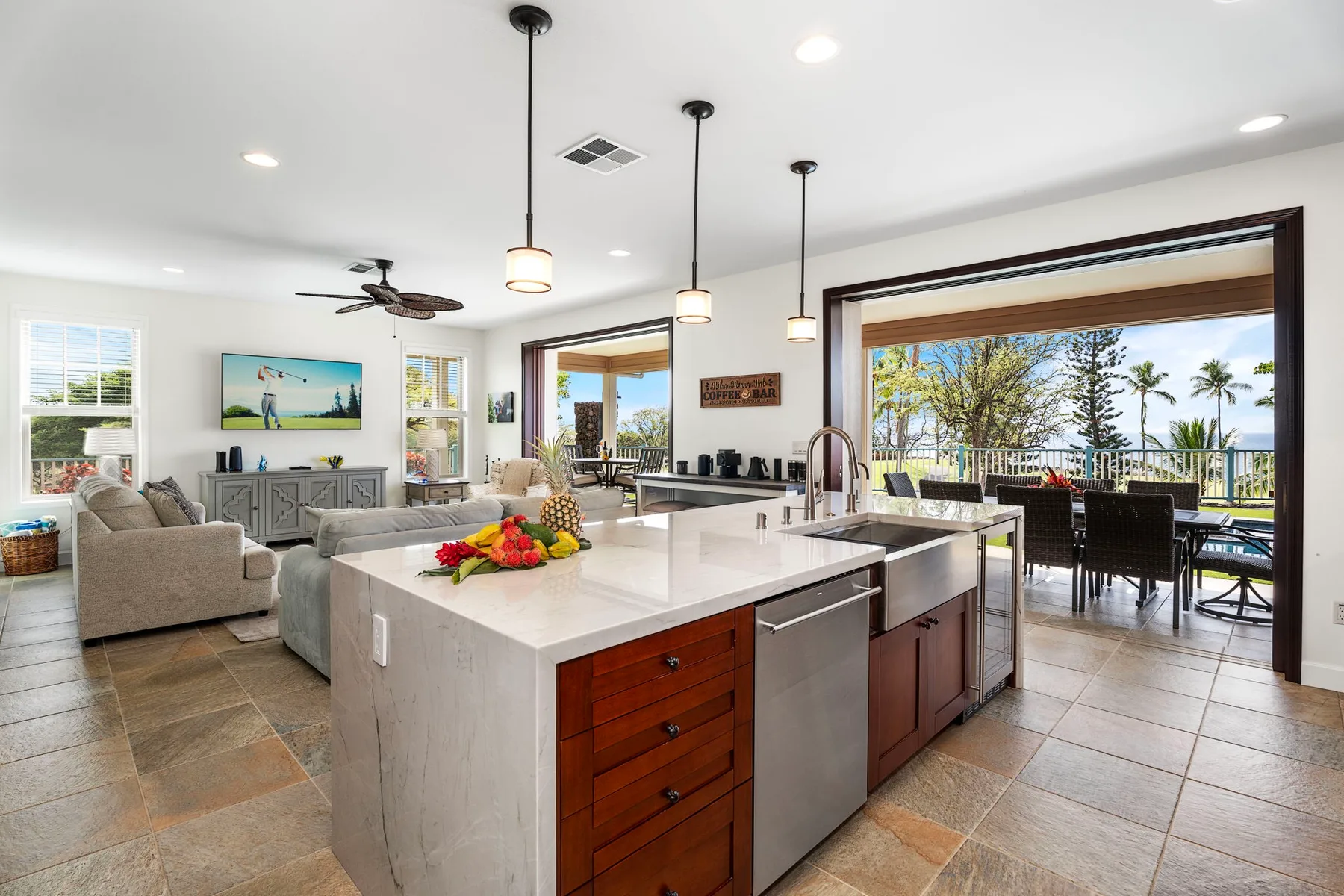 A bright open-plan kitchen and living area opens onto a patio with outdoor seating.