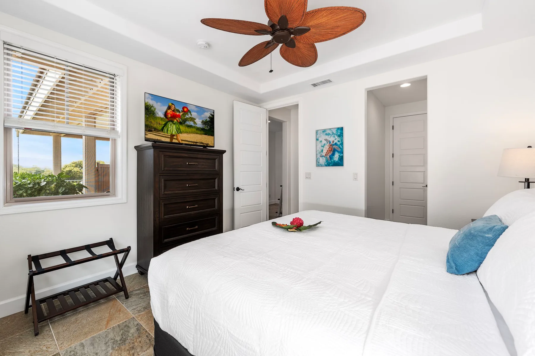 A bright bedroom with a large bed, a dresser, and a window.