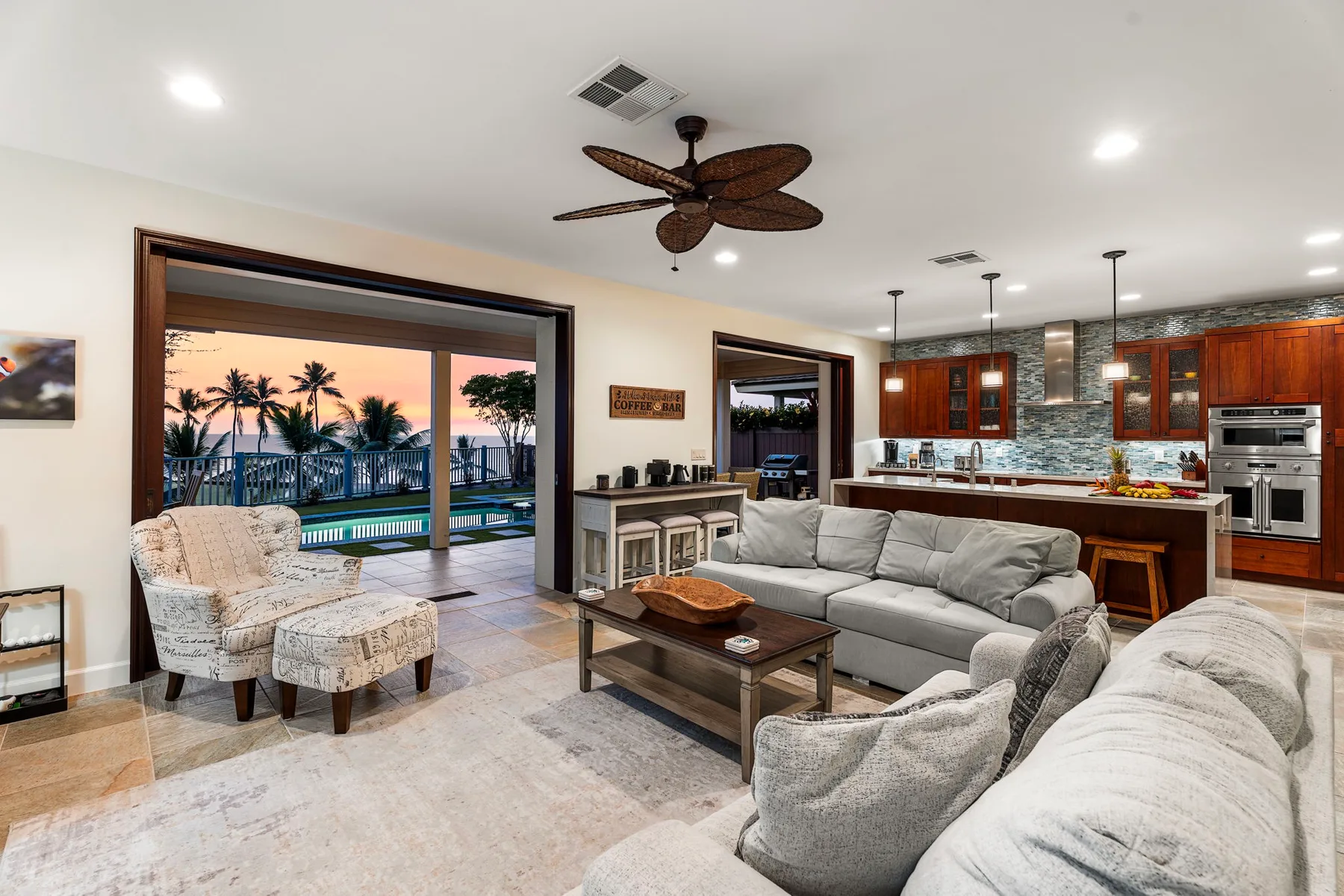 An open-plan living room and kitchen with seating and a large glass doorway.