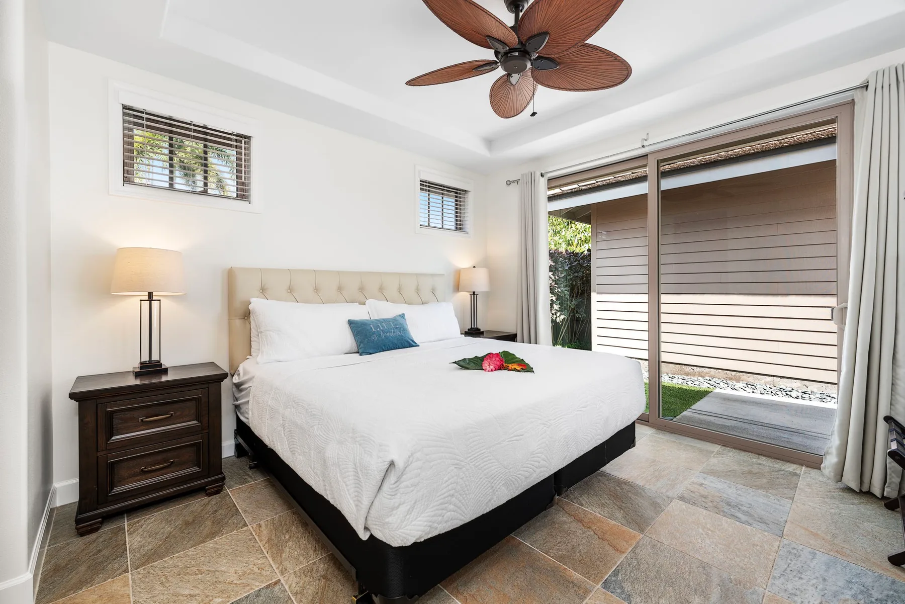 A bright bedroom with a large bed and a sliding glass door.