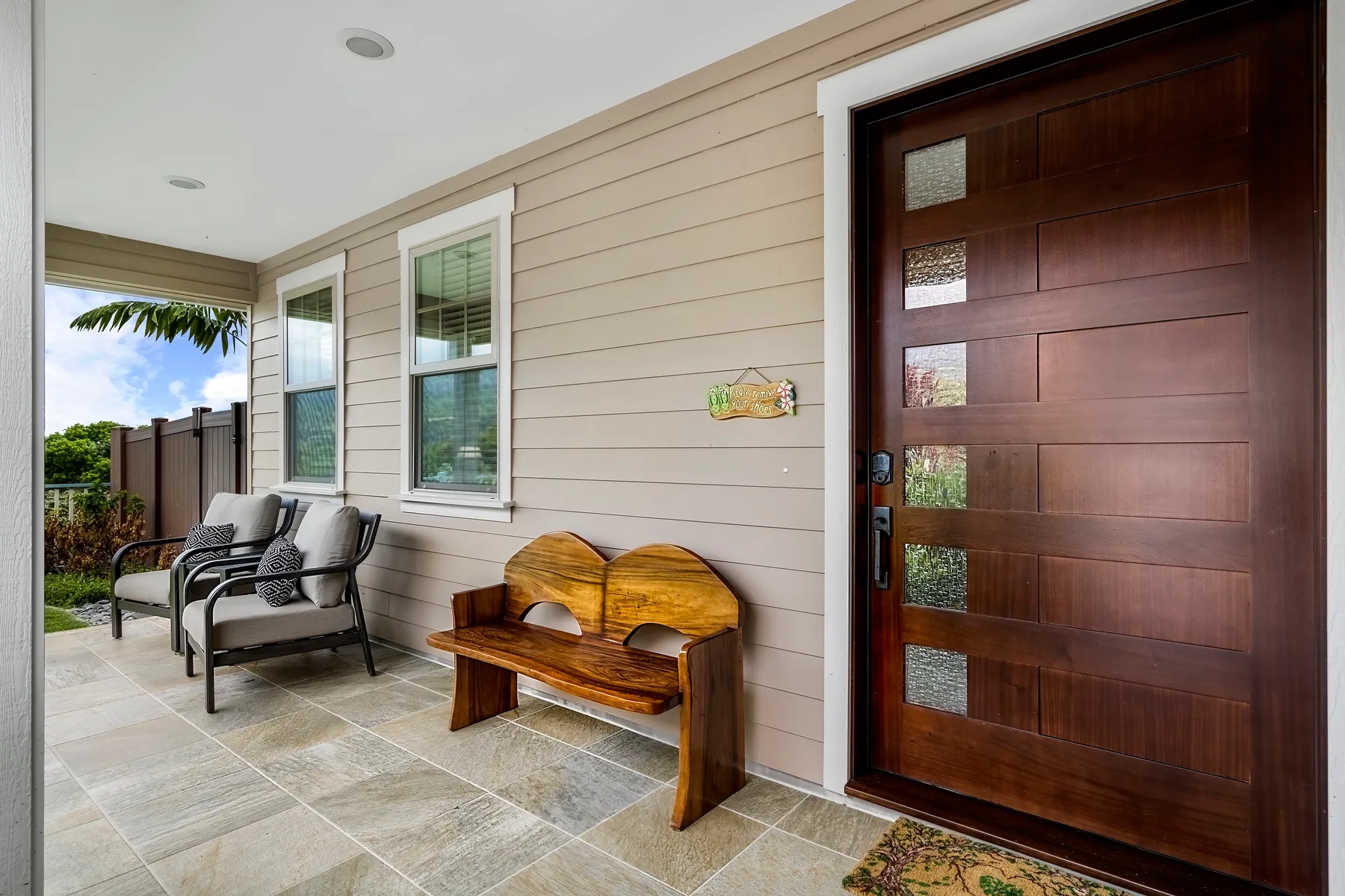 A covered entry patio with seating and a wooden bench beside the front door.