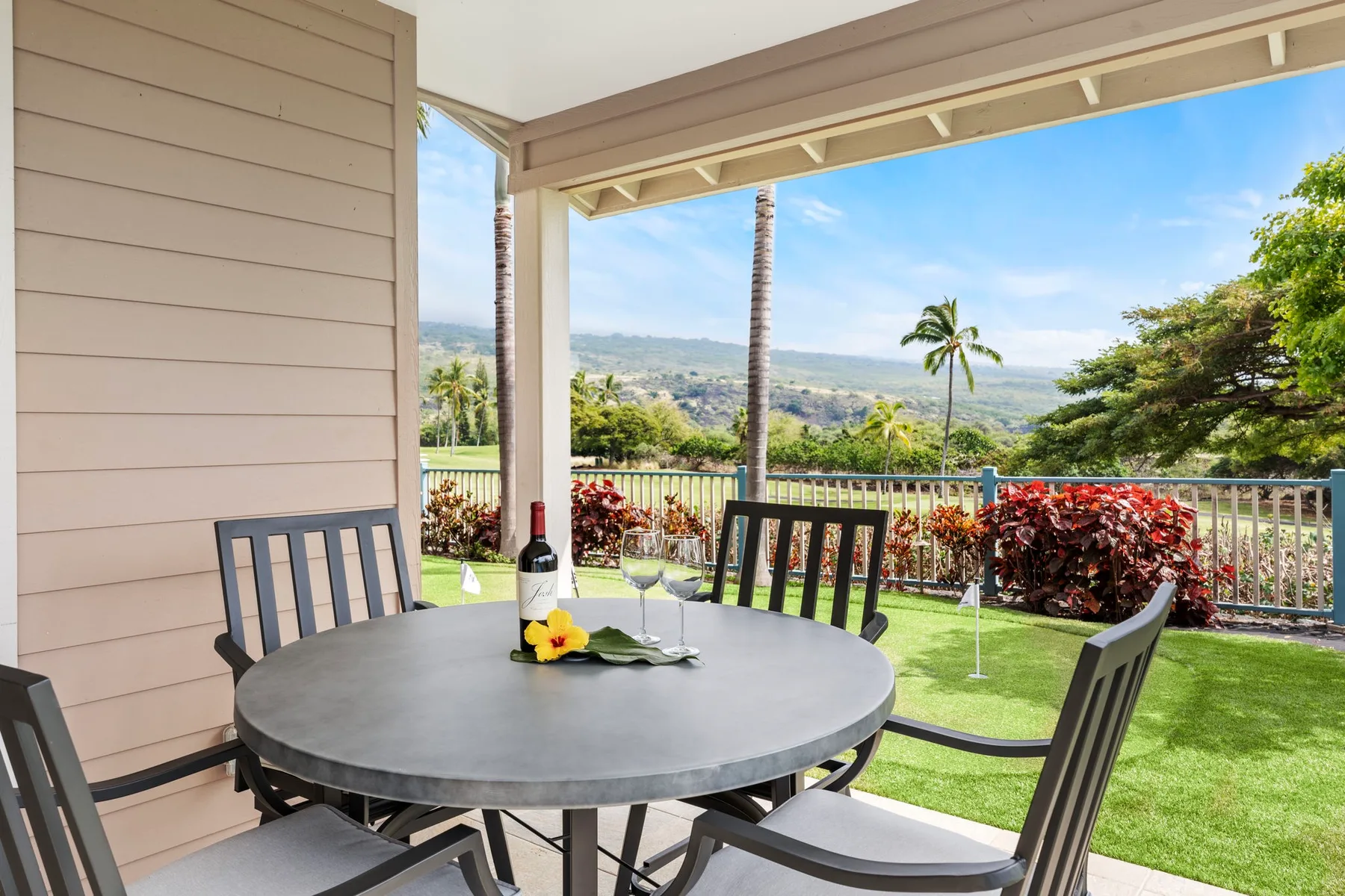 A covered outdoor dining area overlooks a green lawn and distant hills.
