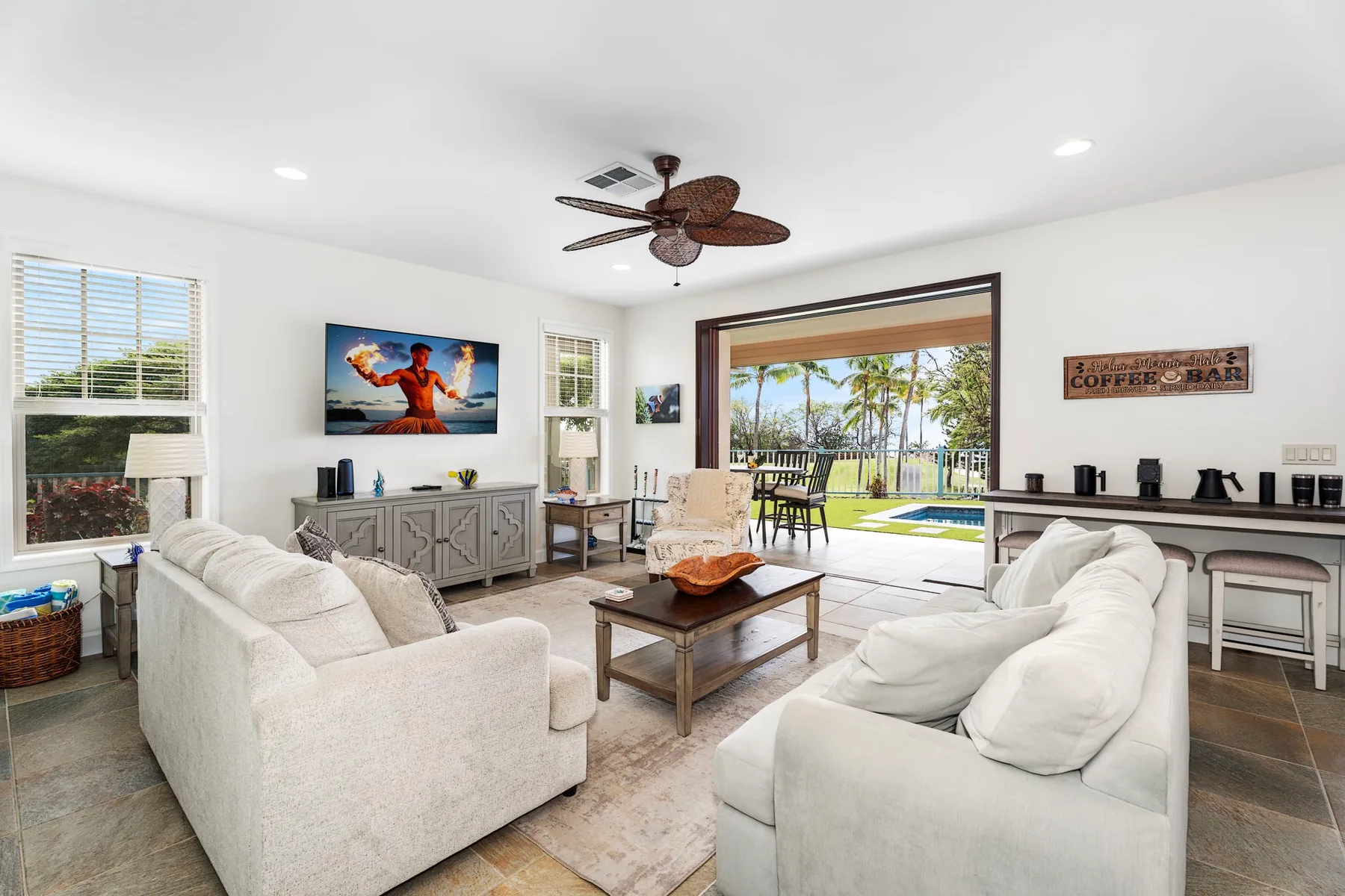 A bright living room with seating around a coffee table and an open view to the patio.