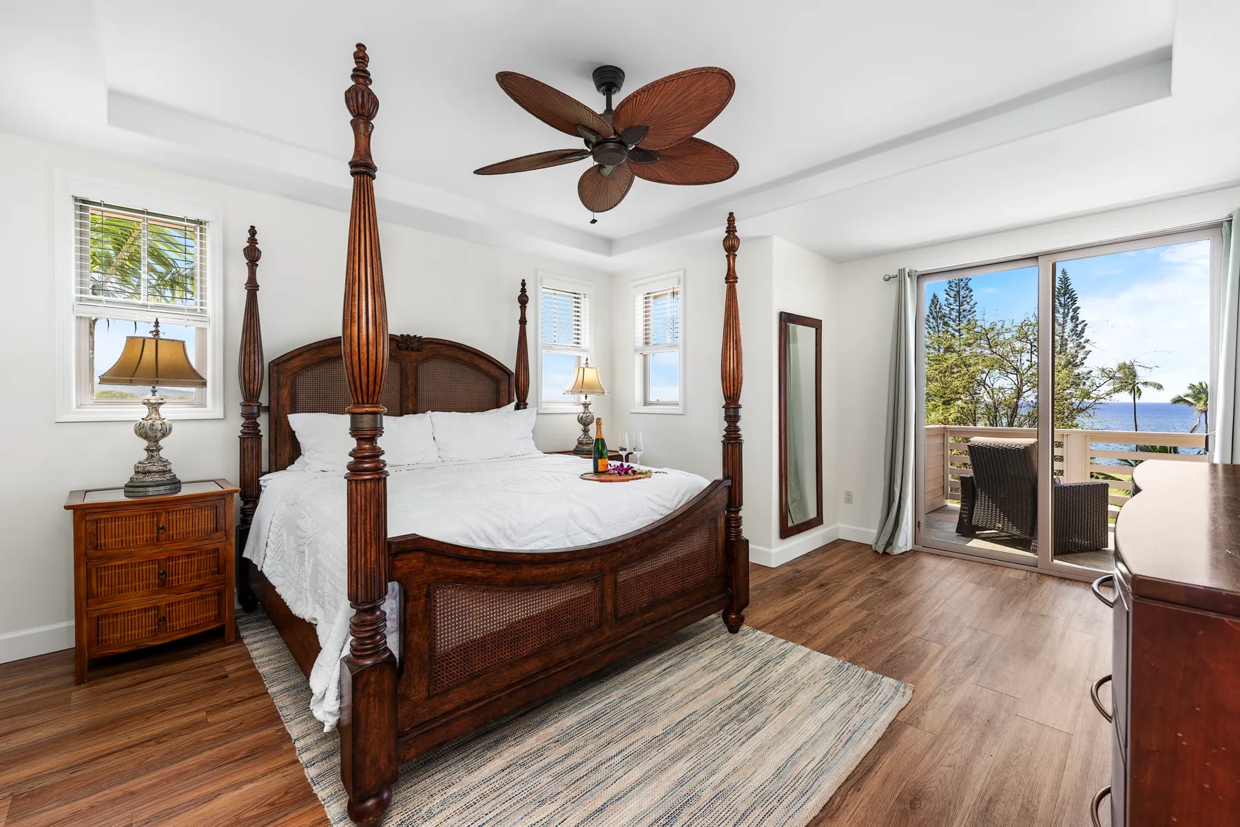 A bedroom with a carved wooden bed, bedside tables, and sliding glass doors opening to a balcony.