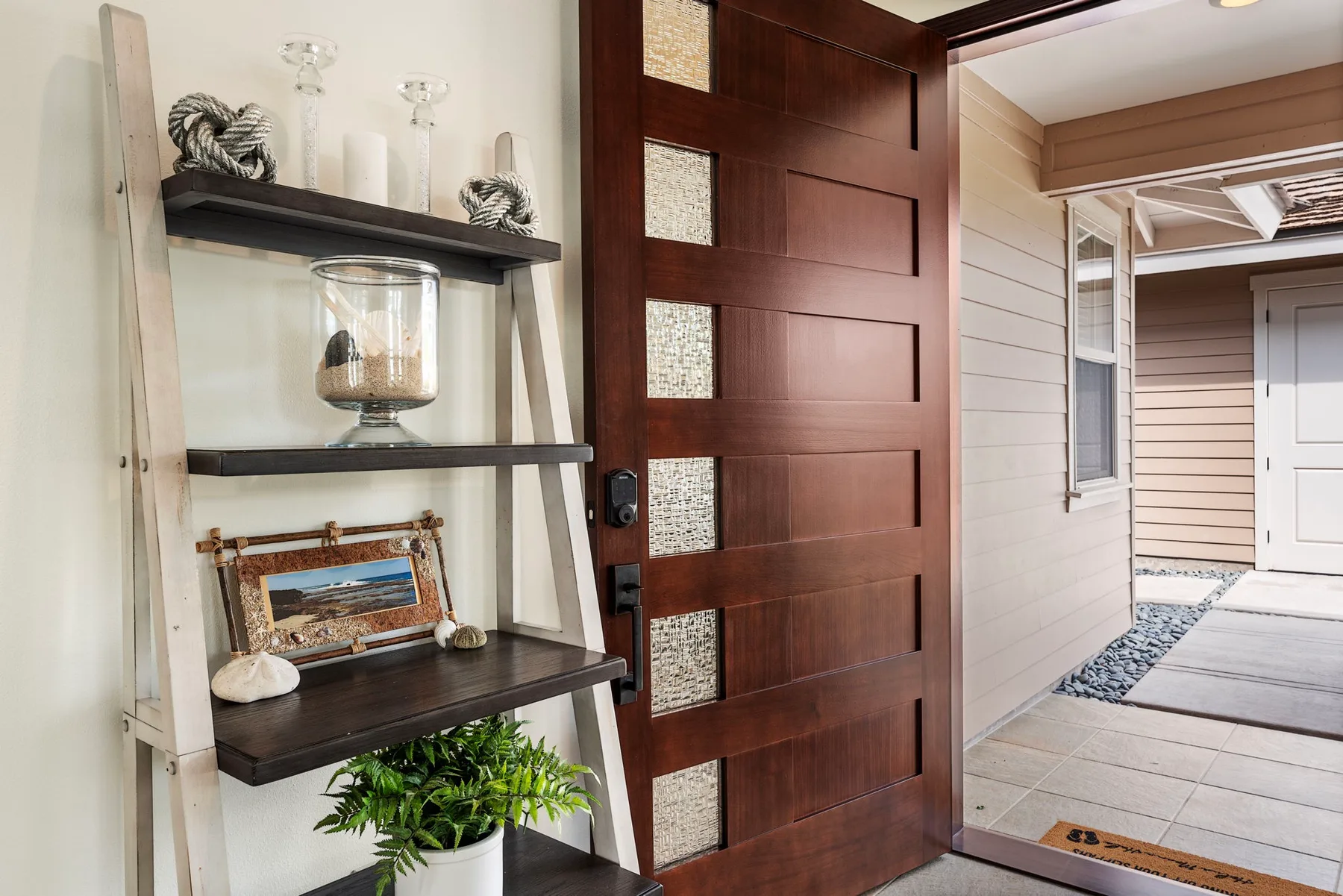An open wooden front door beside a decorative shelving unit.