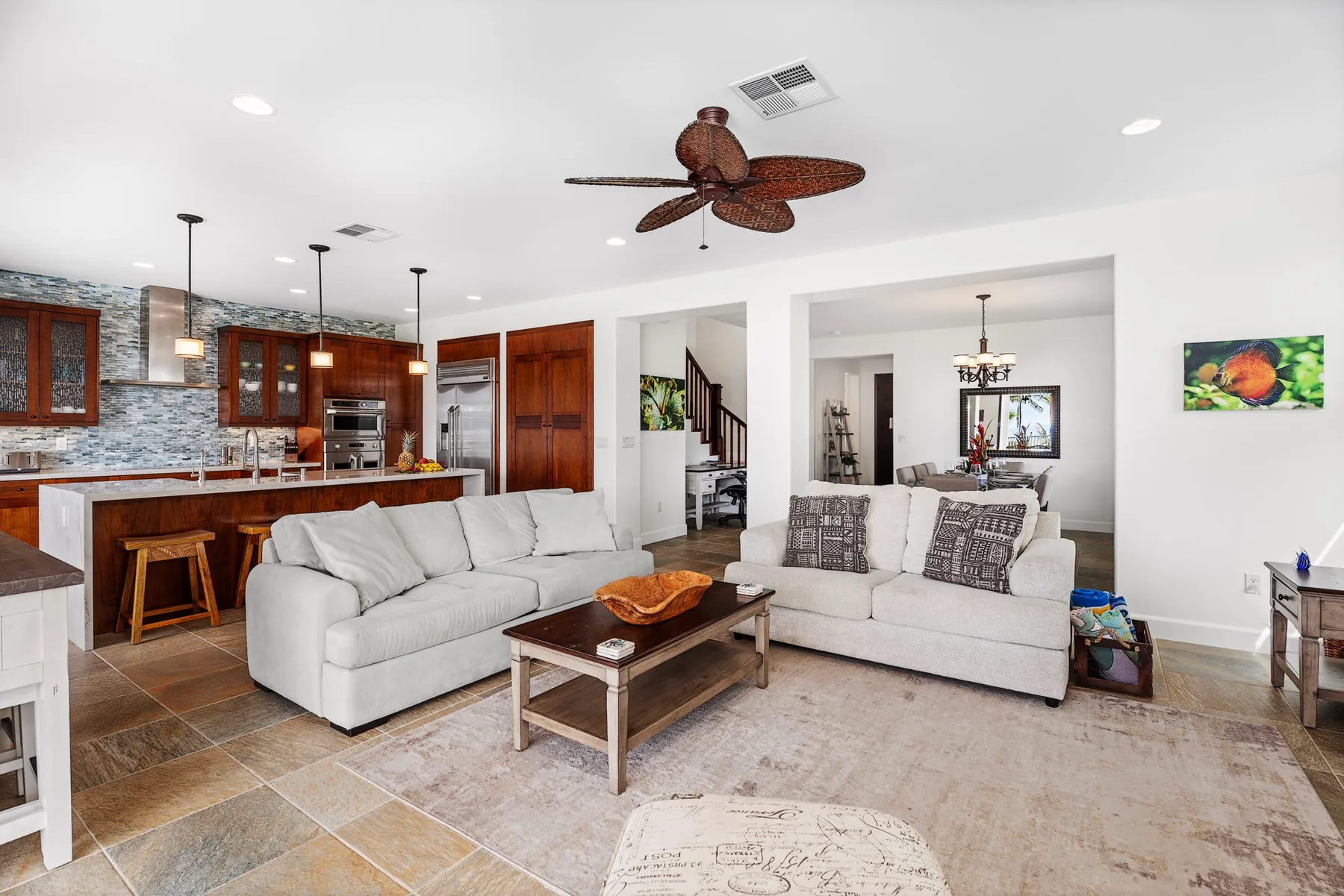 An open-plan living room and kitchen with pale seating and dark wood cabinetry.