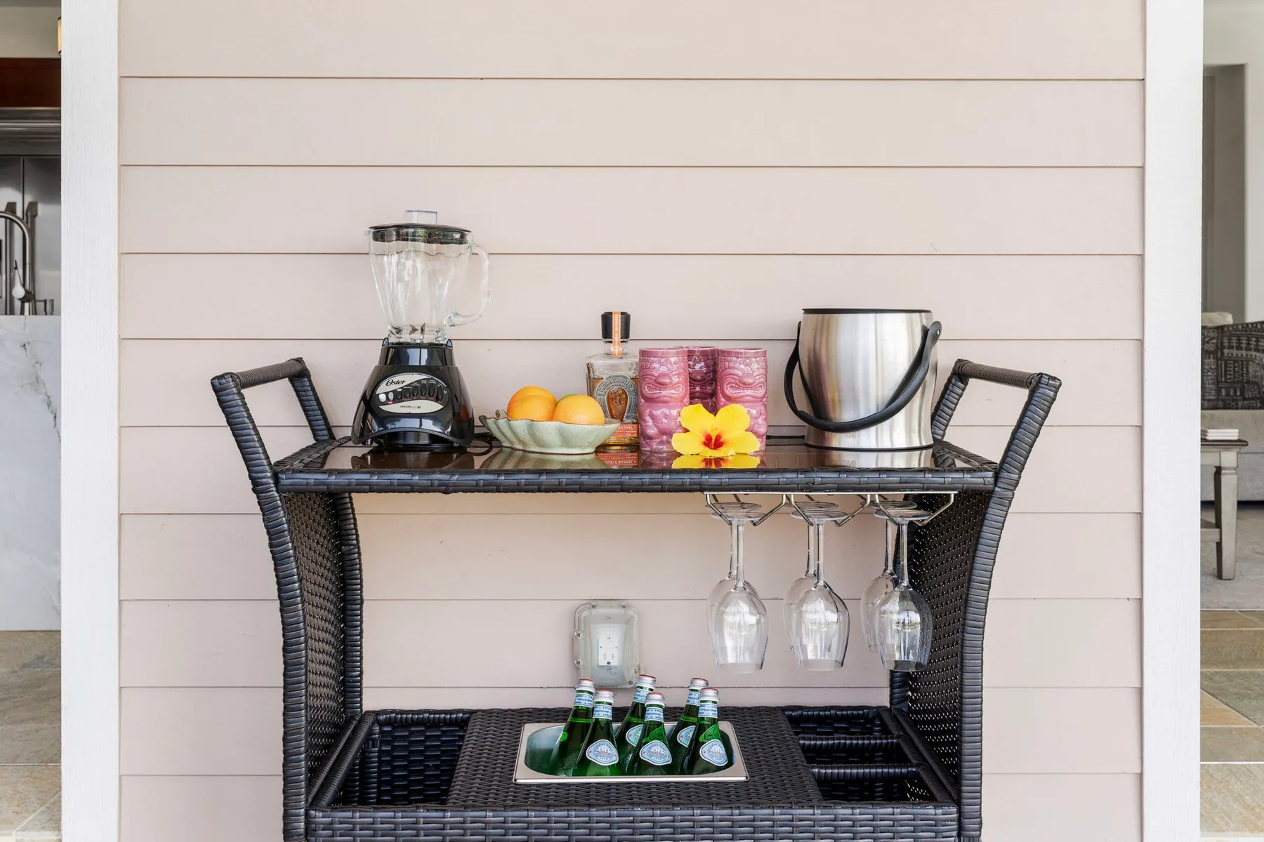 A beverage station with a blender, kettle, glasses, and bottled drinks.