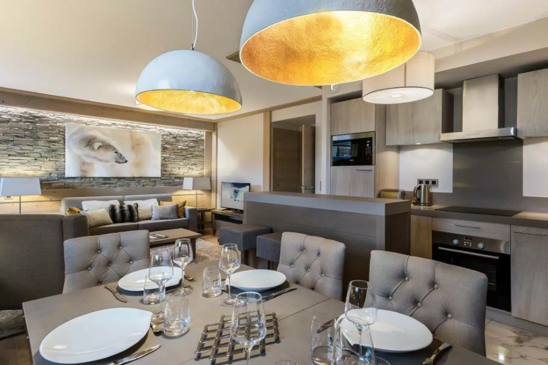 A dining area and open kitchen with pendant lights and a set table.